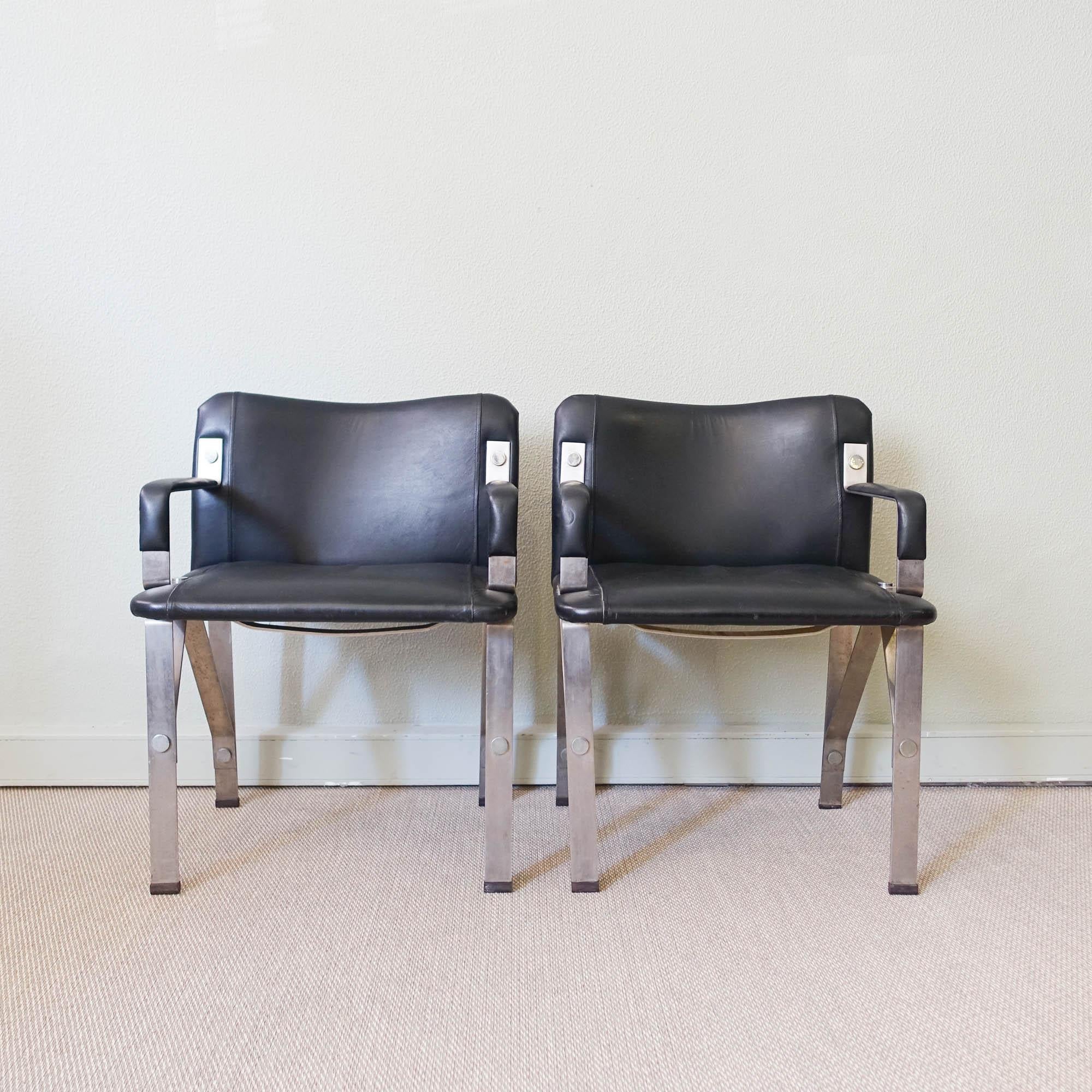 This pair of armchairs, was designed by Gilberto Lopes, in Portugal, during the 1970's. It is a brutalist style, featuring an heavy metal structure with black leather upholstery. This pair is in original and good vintage condition.