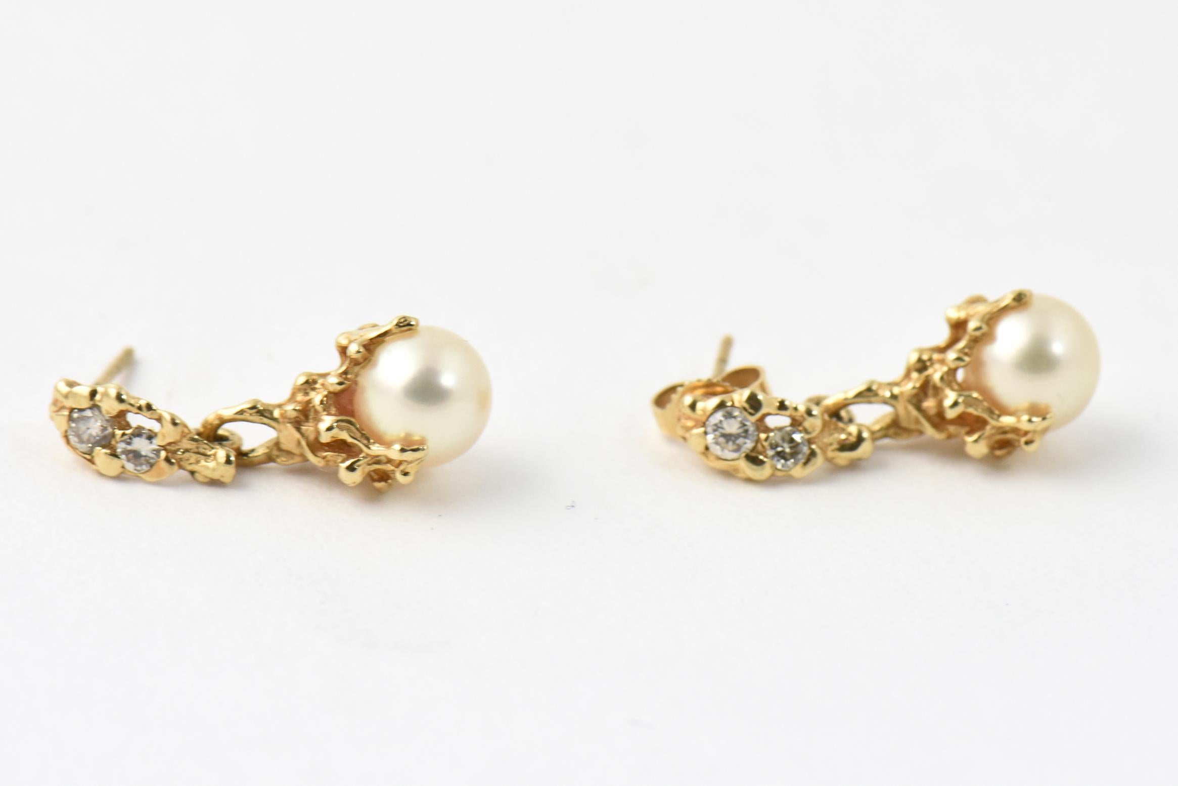7.4 mm cultured pearls dangling from a 1960s - 1970s melted gold brutalist design. The top section has 2 diamonds in each one that are approximately .20 carats total diamond weight. Post earrings with a pair of push on backs.
