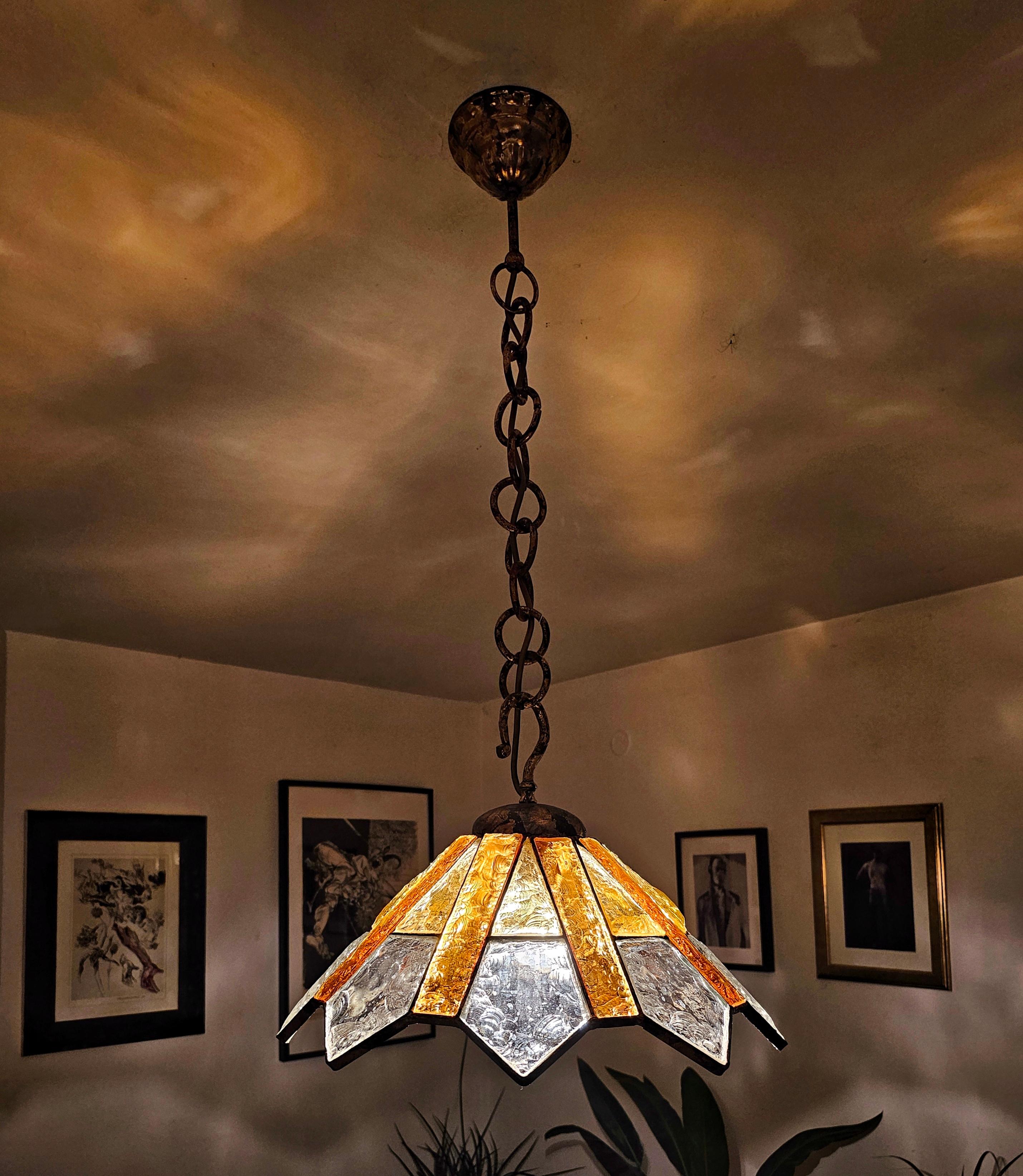 Vous trouverez dans cette annonce une lampe suspendue extrêmement rare, conçue par Longobard. Elle est réalisée en verre clair et ambre martelé, placé dans un luminaire en fer forgé plaqué or. Fabriqué en Italie dans les années 1970.

Très bon état