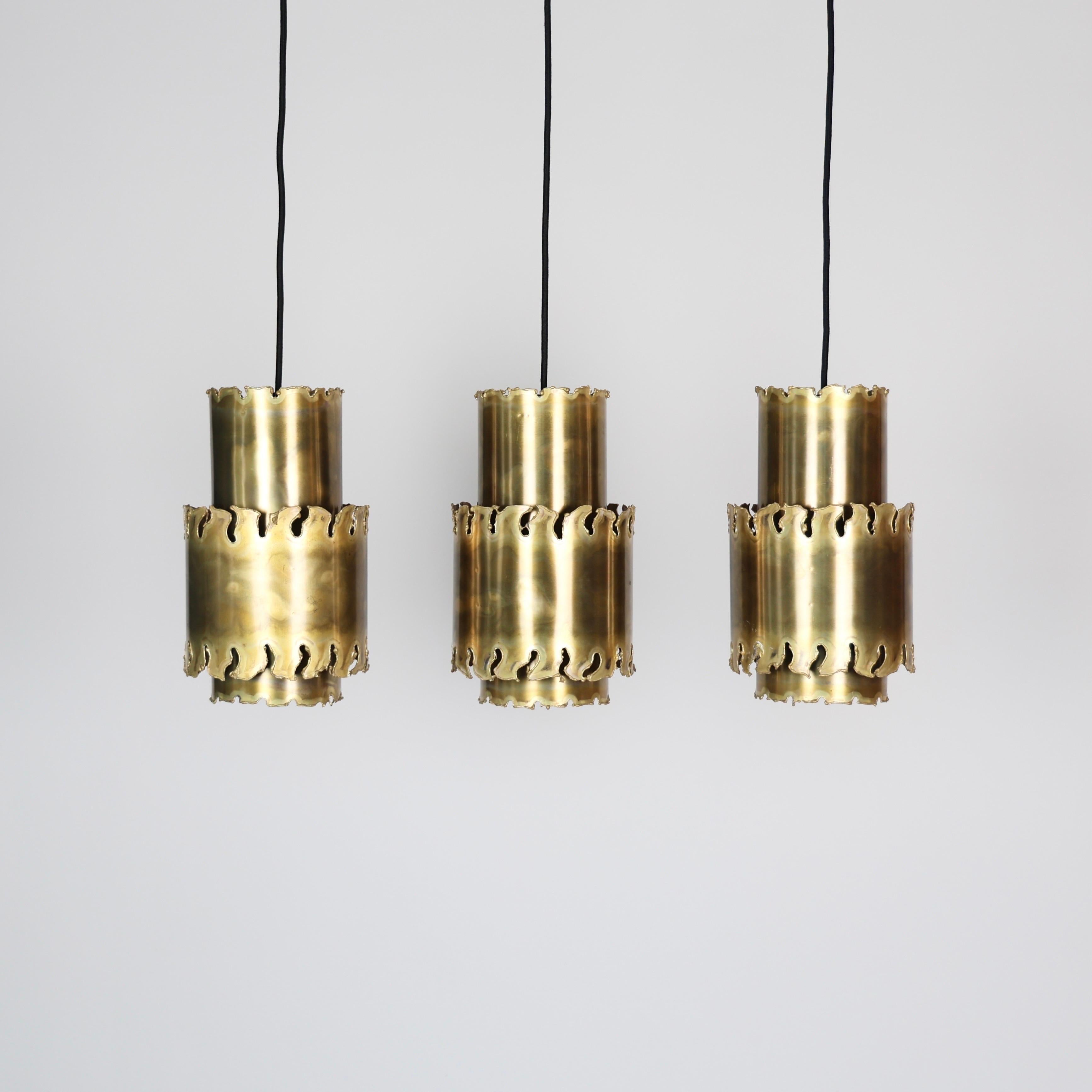 Trio of Brutalist Flame-cut Brass Pendant Lights designed Svend Aage Holm Sørensen in the 1960s. 

* Three (3) tube-shaped pendant flame-cut brass pendant lights
* Designer: Svend Aage Holm Sørensen
* Type: 6400
* Producer: Holm Sørensen & Co.,
