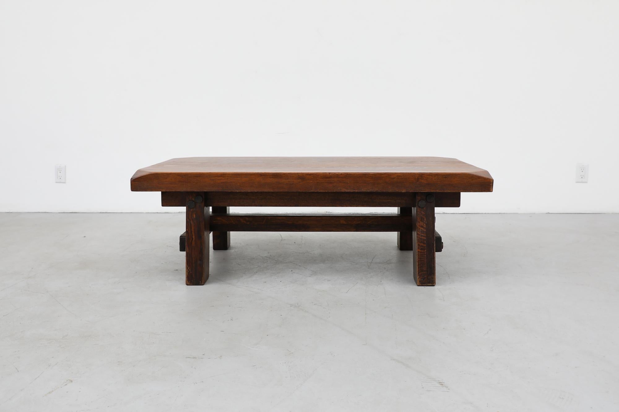 Brutalist midcentury coffee table inspired by Pierre Chapo made from thick solid oak. The table has hefty legs and a sturdy support beam. The frame is fastened together with large pegs. In original condition with visible wear, consistent with its