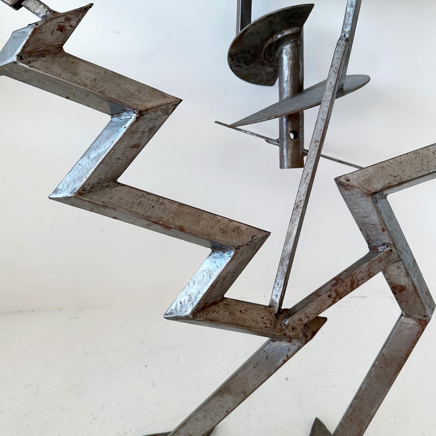 One of a kind welded brushed steel console table with glass top. Cartoonish, playful jagged zig zags alongside shapes that recall boating or aviation e.g. propellers/blades. 

The glass pieces on top are inset and easily removed/changeable. The long