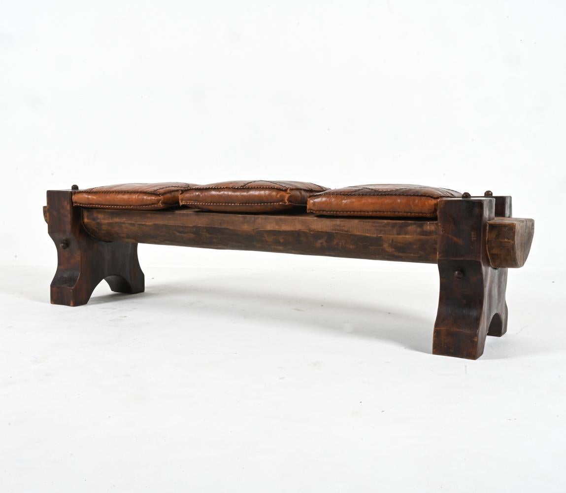 Recently imported from Europe, this unique and showstopping statement bench appears to have been hand-hewn from segments of solid exotic wood. Honoring the shape of the original tree trunk, the seat is a beautiful and substantial half-cylinder,