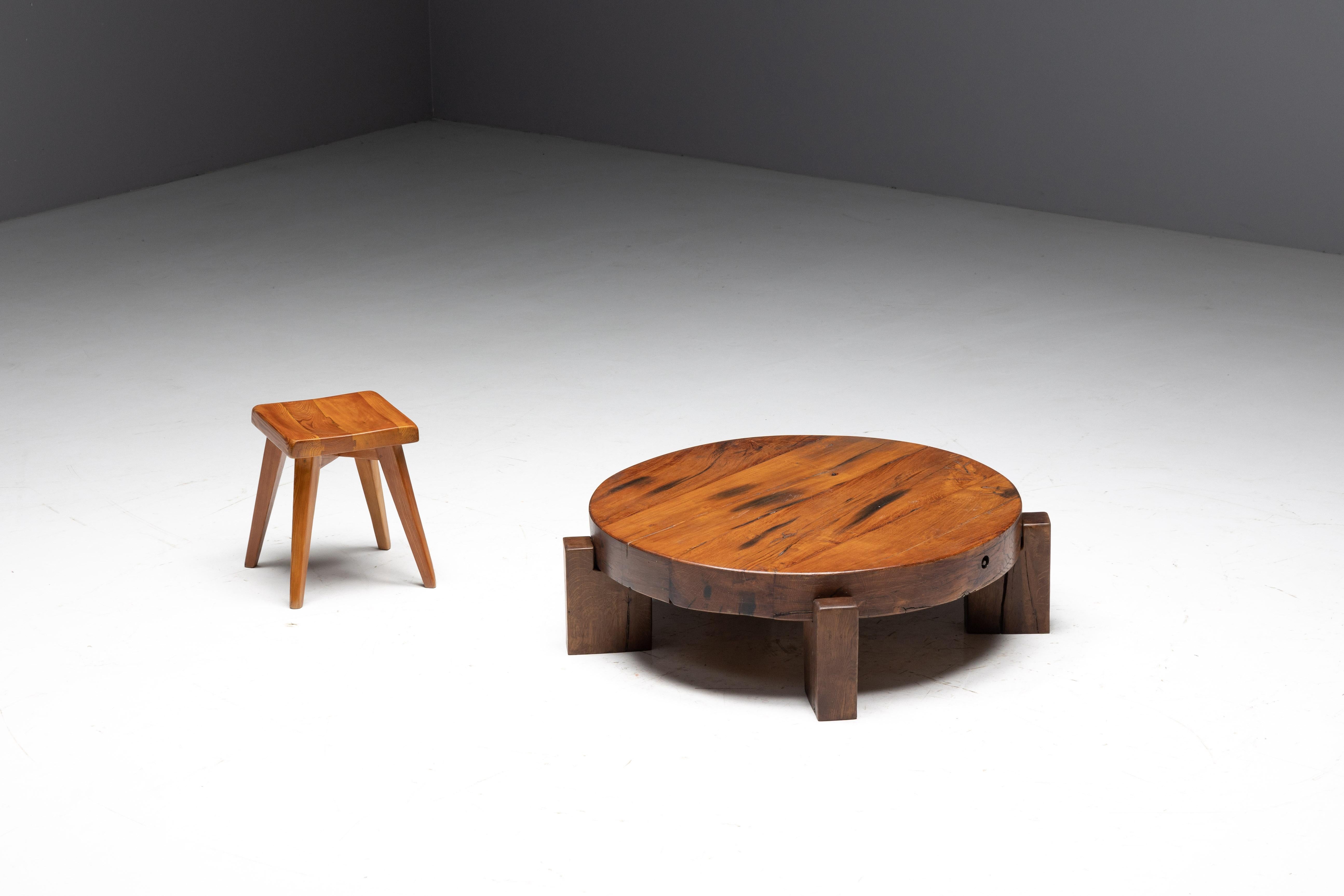 Brutalist round wooden coffee table with a four-legged base, crafted from solid wood with a charismatic patina. Its seamless integration of tabletop and legs offers a unique twist, making it a standout piece in any setting. With plenty of surface