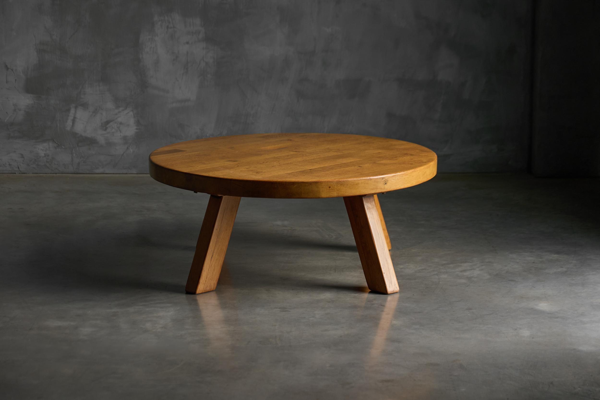 This round coffee table embodies a 1960s Brutalist aesthetic, crafted from solid wood with a bold, sculptural presence. Its thick, weighty top and angled block legs emphasize raw simplicity and structural honesty. The warm patina and visible grain