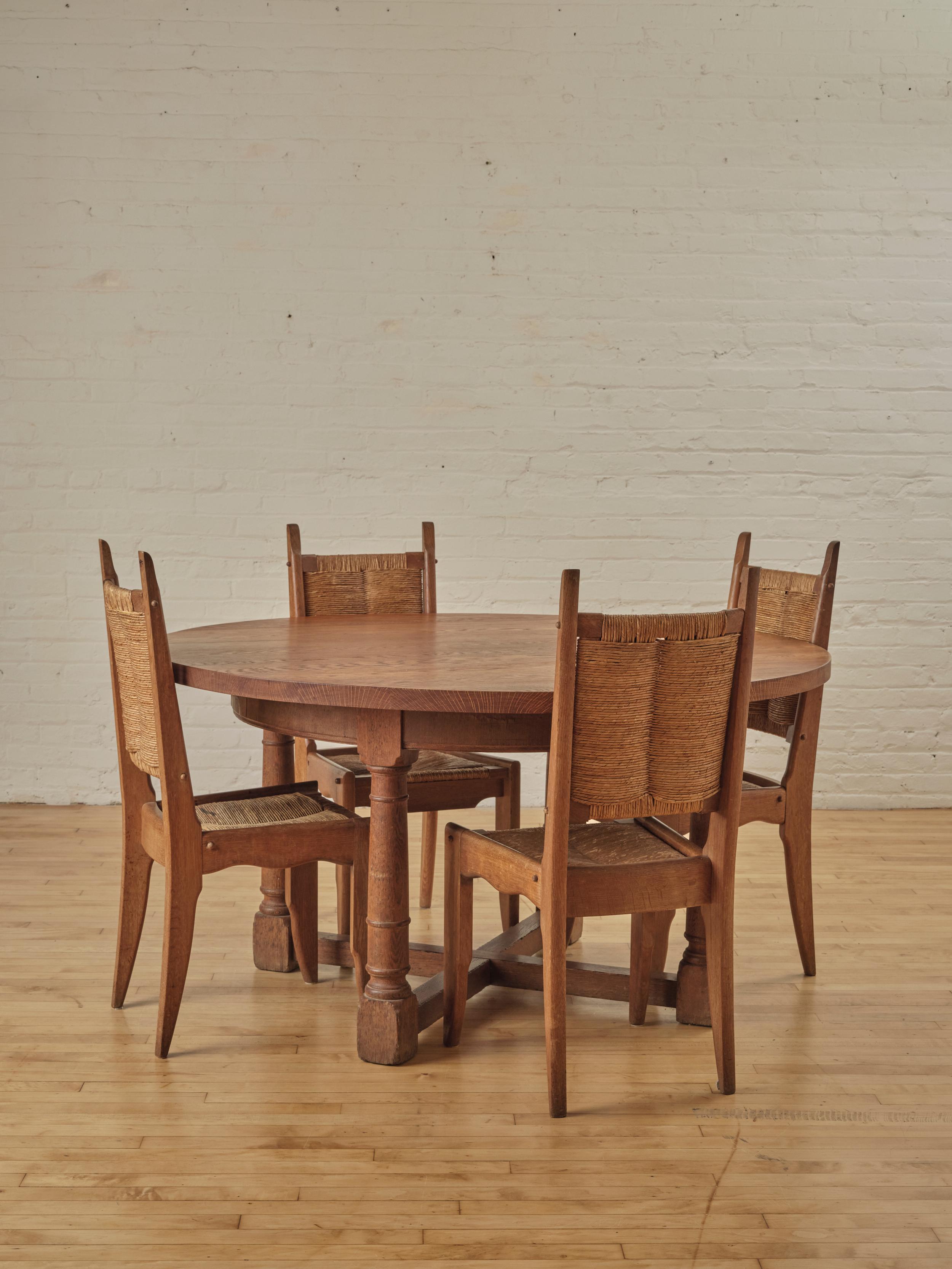 Table de salle à manger circulaire du début des années 1900, fabriquée en bois de chêne avec quatre pieds joints.

