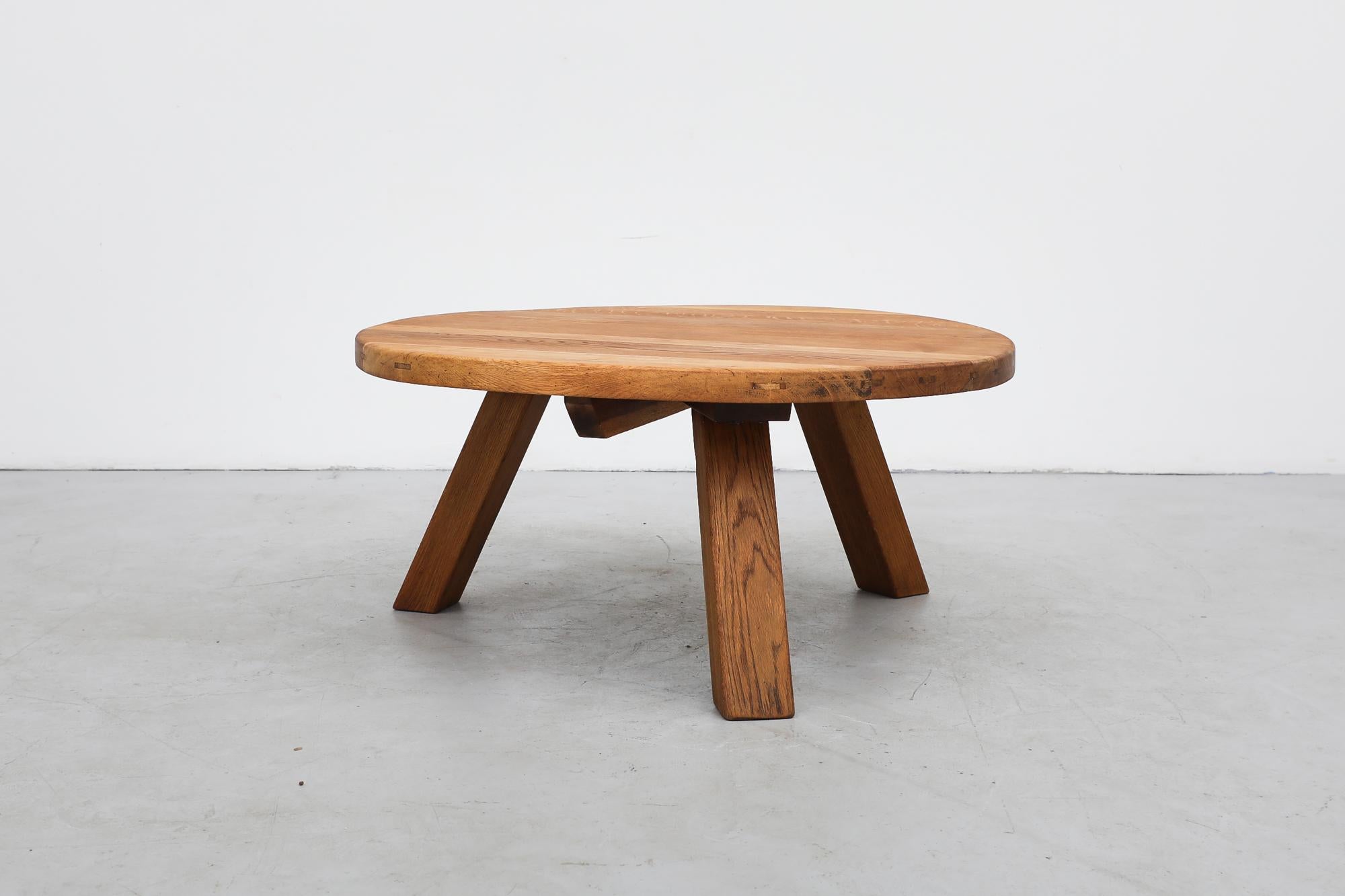 Brutalist heavy round coffee table is made from solid oak and has three sturdy square legs. In original condition with visible wear and patina consistent with its age and use.