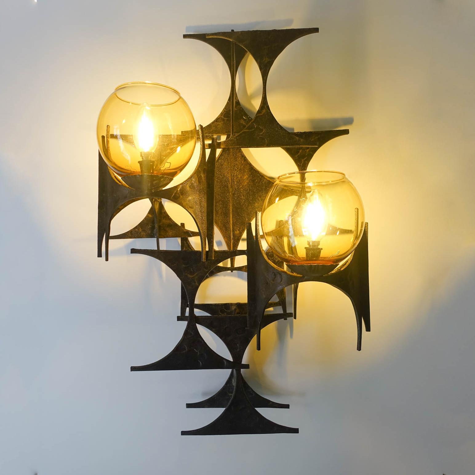 This brutalist sconce was designed and produced by Marc Weinstein, in USA, during the 1960's. This iron sconce is made of metal hourglass-shaped pieces that have been layered and soldered together with a brush copper and bronze patina, were two