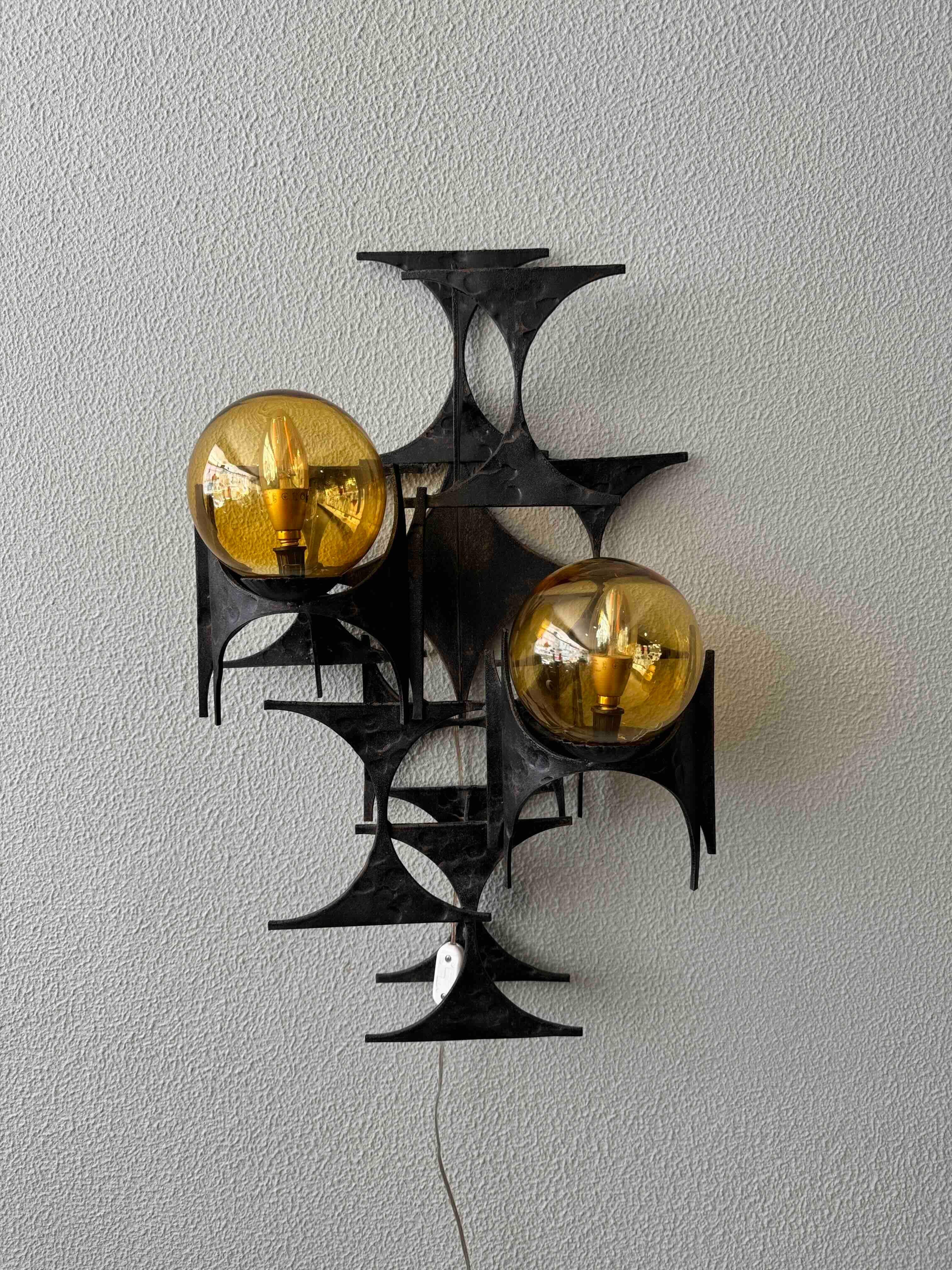 Cette applique brutaliste a été conçue et produite par Marc Weinstein aux États-Unis dans les années 1960. Fabriquée en fer, cette remarquable applique présente des pièces métalliques en forme de sablier qui ont été méticuleusement superposées et