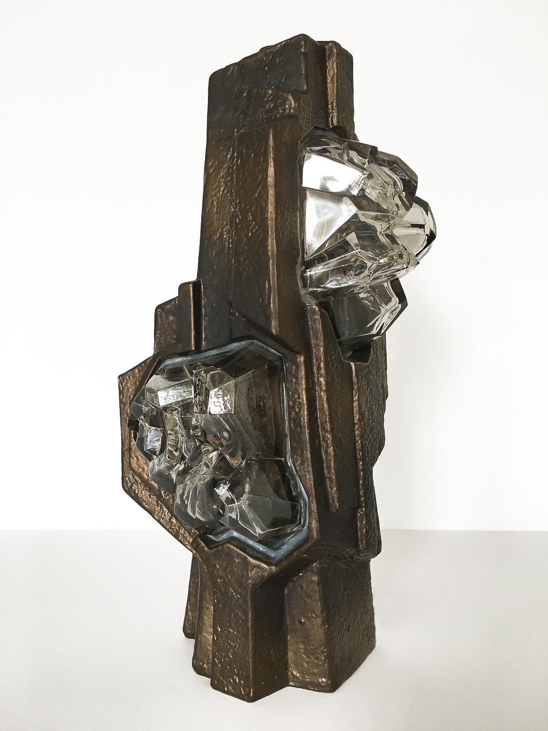 Unique and unusual sculptural rock and crystal formation table lamp in glazed ceramic and glass. Brutalist in form, this table lamp features a dark bronze glazed ceramic body with two thick faceted clear glass windows. The glass is intended to