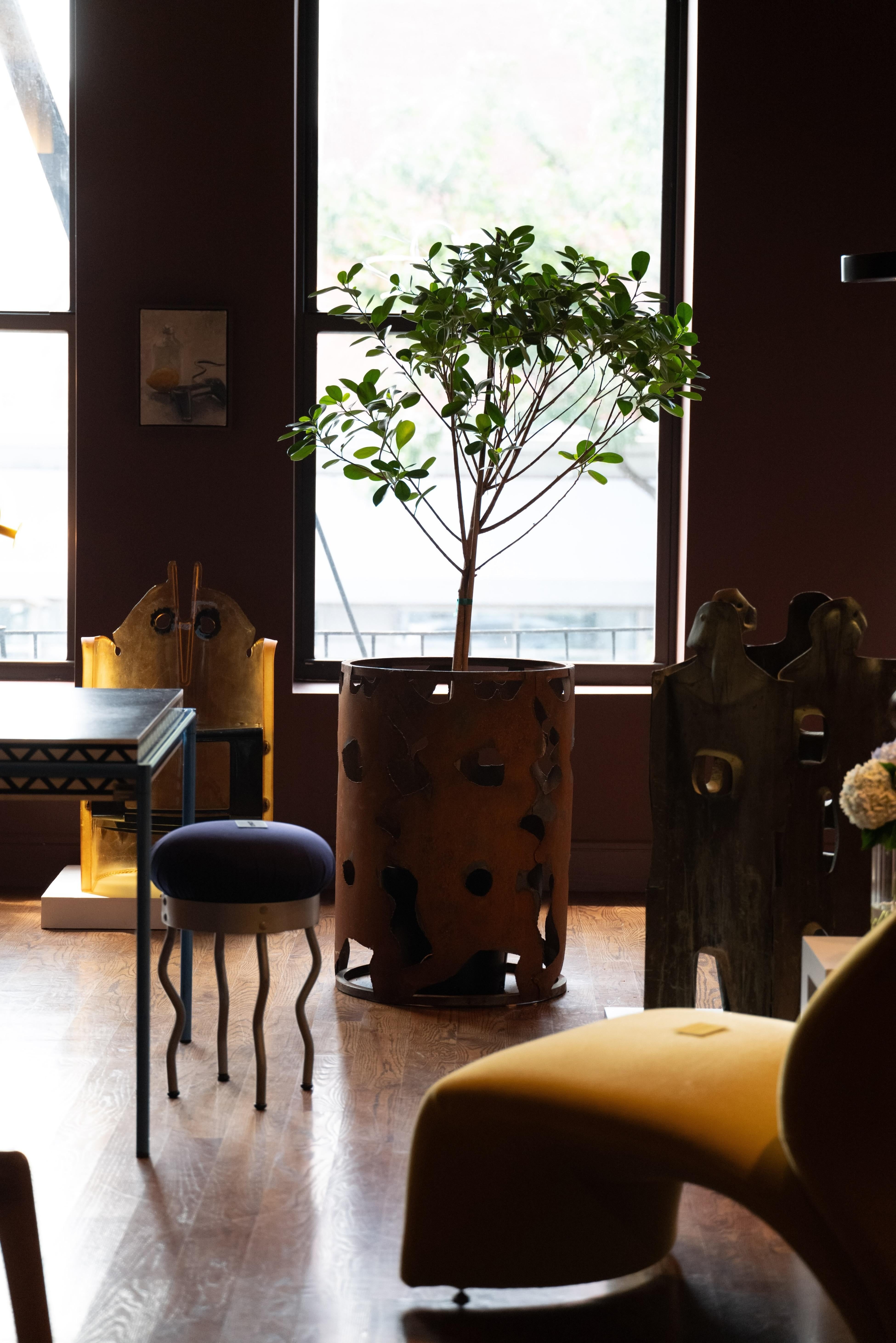 Cette table d'appoint sculpturale présente un socle cylindrique en acier à la silhouette expressive, taillée à la main. La patine oxydée rehausse sa texture brute et organique, évoquant la beauté robuste du métal usé par les intempéries. Les espaces