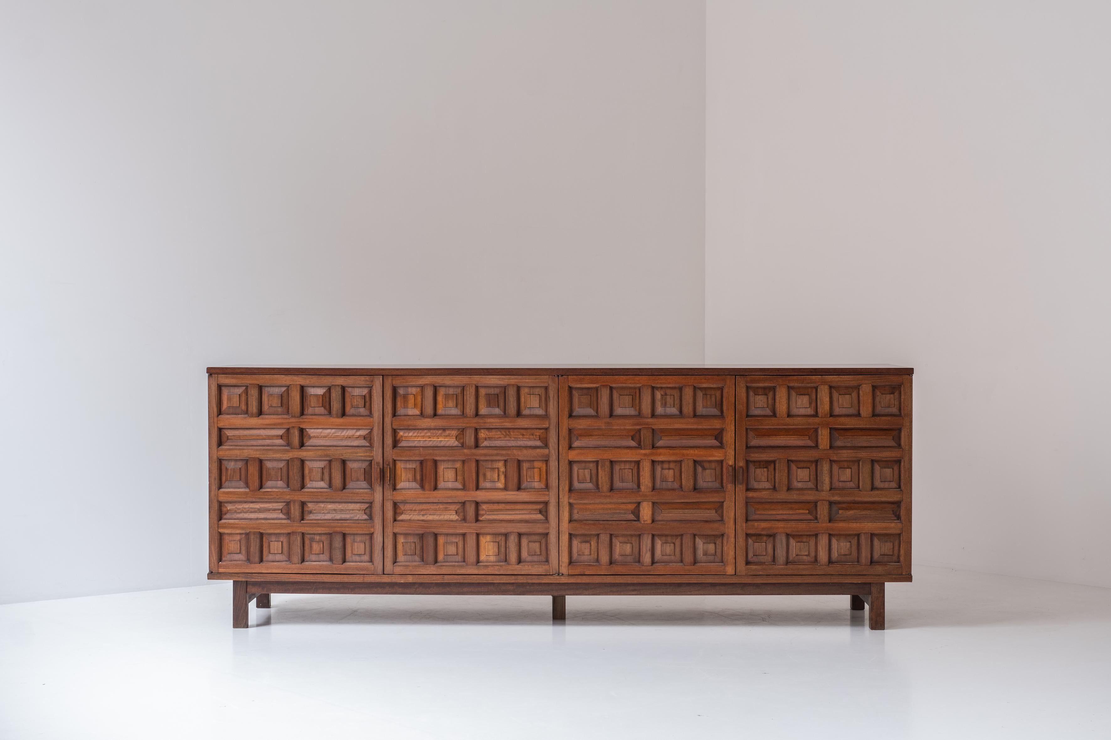 Brutalist sideboard from Spain, designed and manufactured in the 1970s. This credenza is made out of stained walnut and features a series of repeating carved patterns, which give the sideboard a strong appearance. Each door covering a shelf and