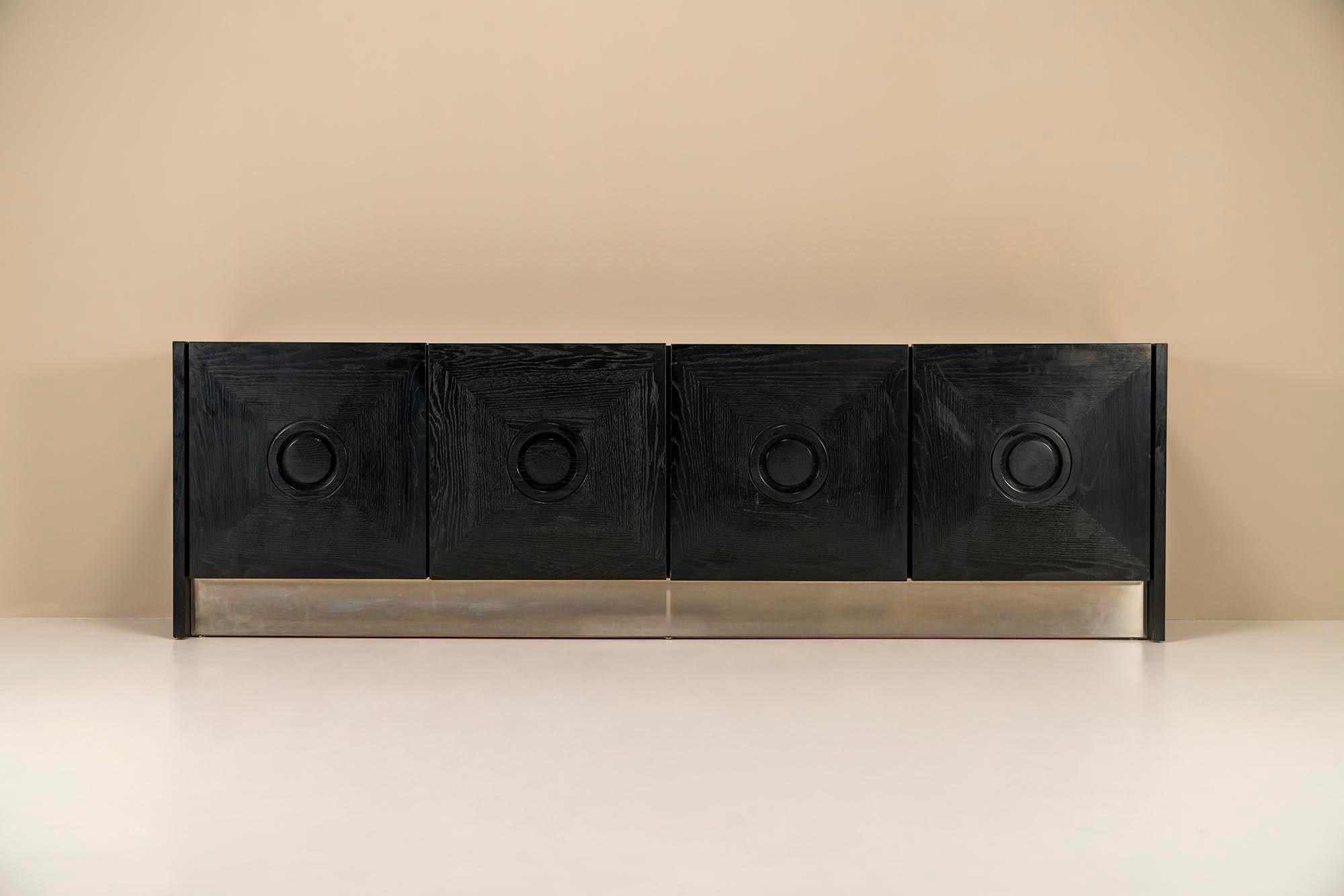 Brutalist sideboard in black stained oak and brushed steel.This sideboard has a really impressive look due to the sleek finish of the glossy wood and steel strip of brushed steel. The genre to which this sideboard belongs is brutalism and in