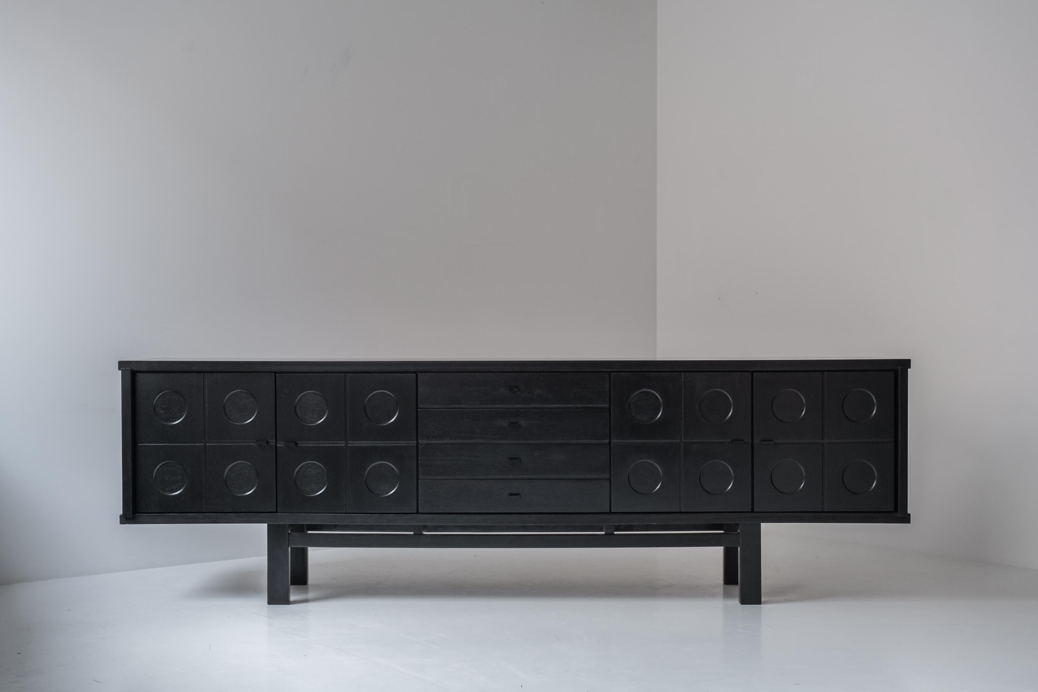 Brutalist sideboard from the 1970’s. This credenza is made out of ebonized oak and is often attributed to De Coene. It features four decorative graphic door paneles covering a shelf inside. In the middle you can find a series of drawers. Presented