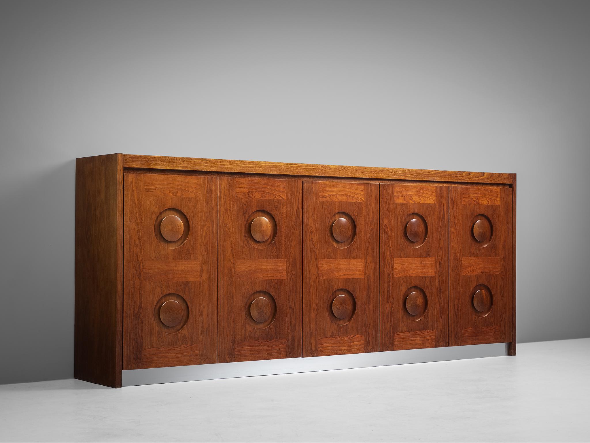 Brown Brutalist credenza in mahogany and aluminum, European, 1970s. 

Sturdy credenza in mahogany with graphical designed door panels. Five-door panels, each with a three-dimensional pattern of circles horizontal lines, which gives the cabinet a