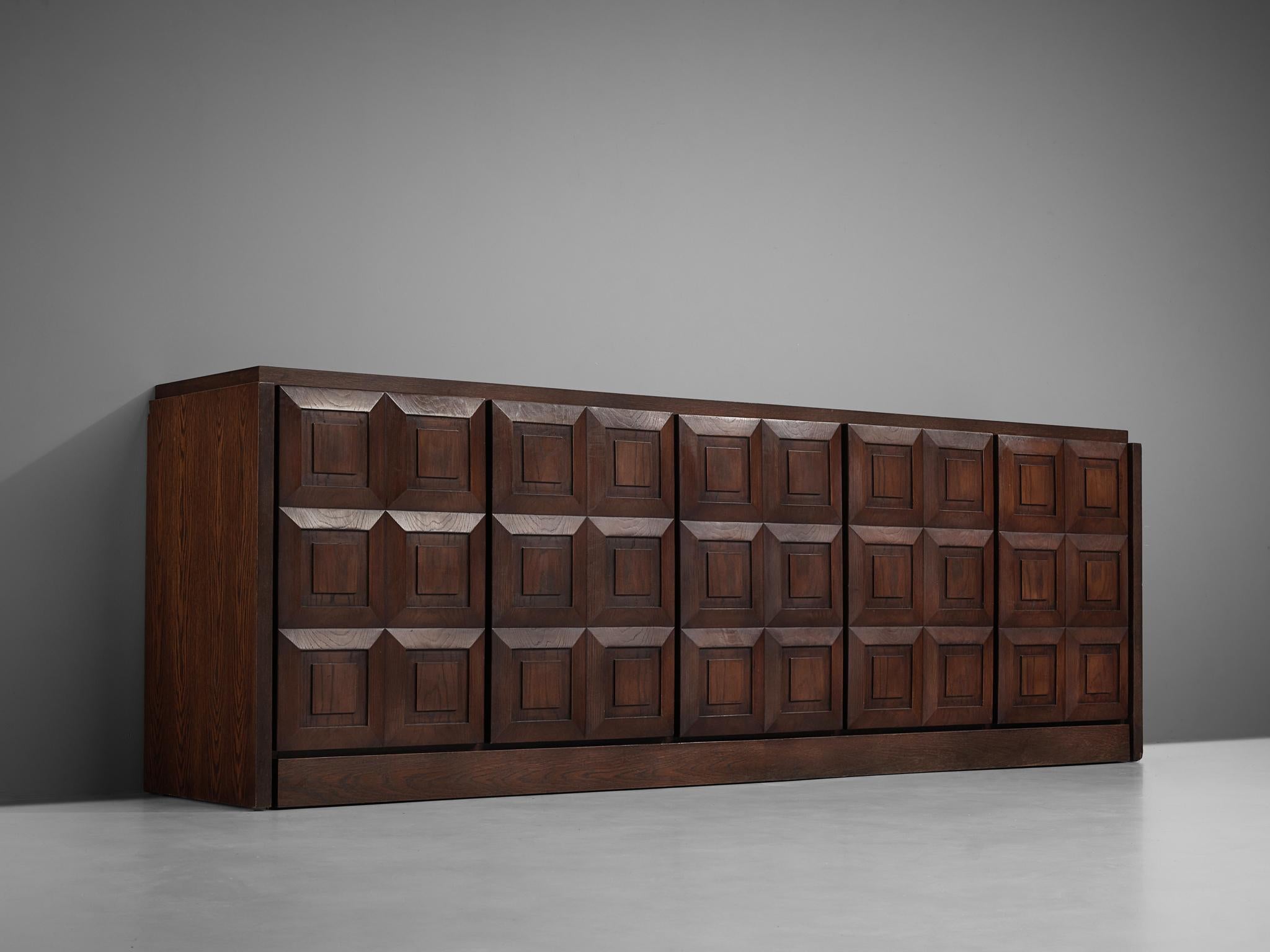 Sideboard, stained oak, Belgium, 1970s. 

This very evocative credenza features a clear rhythm and flow established by means of a well thought through lay out that is utterly well-balanced. The carved squares immediately catch the eye and are the