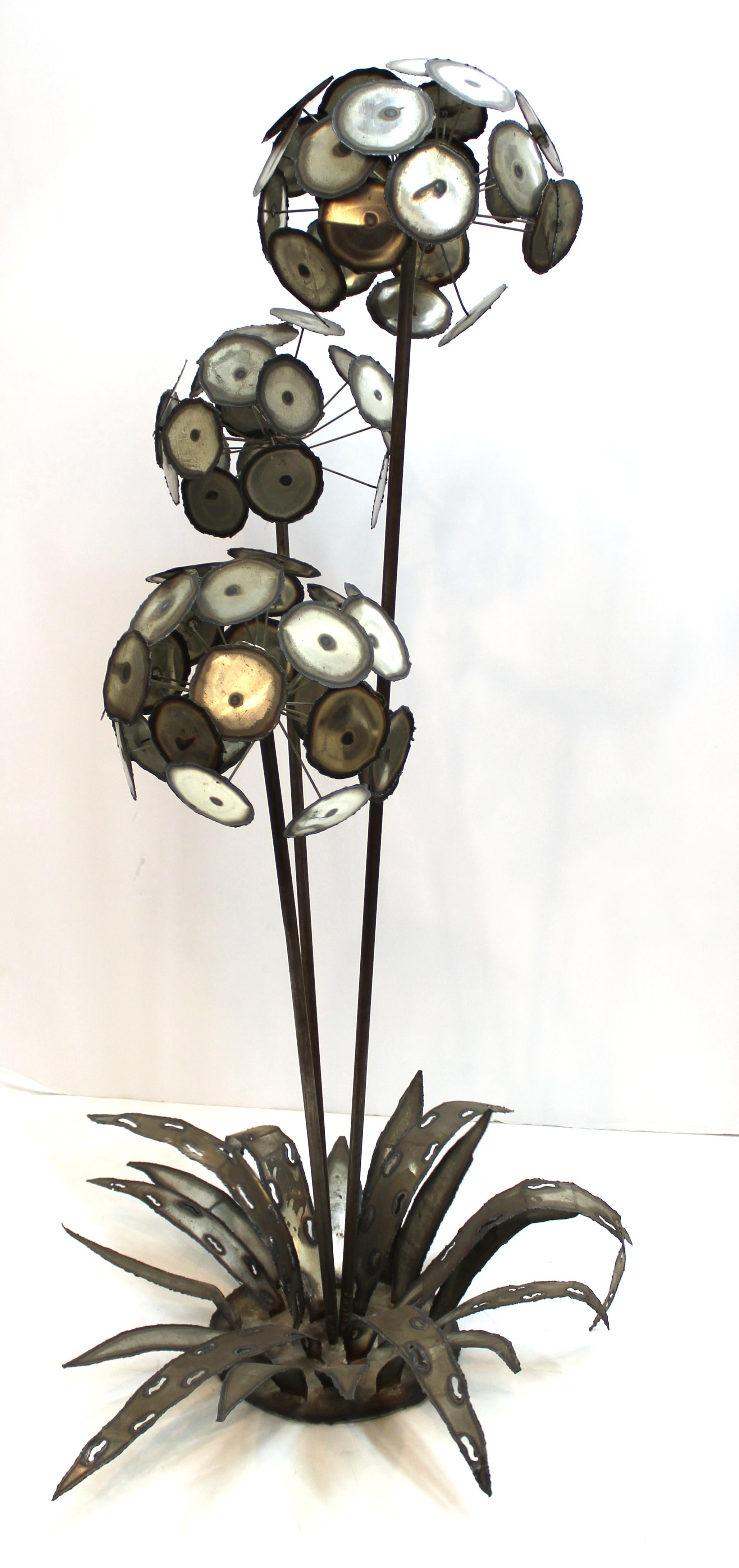Brutalist monumental sized metal flower sculpture consisting of three flower heads on a base with leaves. One of the leaves has an illegibly signed metal tag. In good vintage condition with age-appropriate patina.