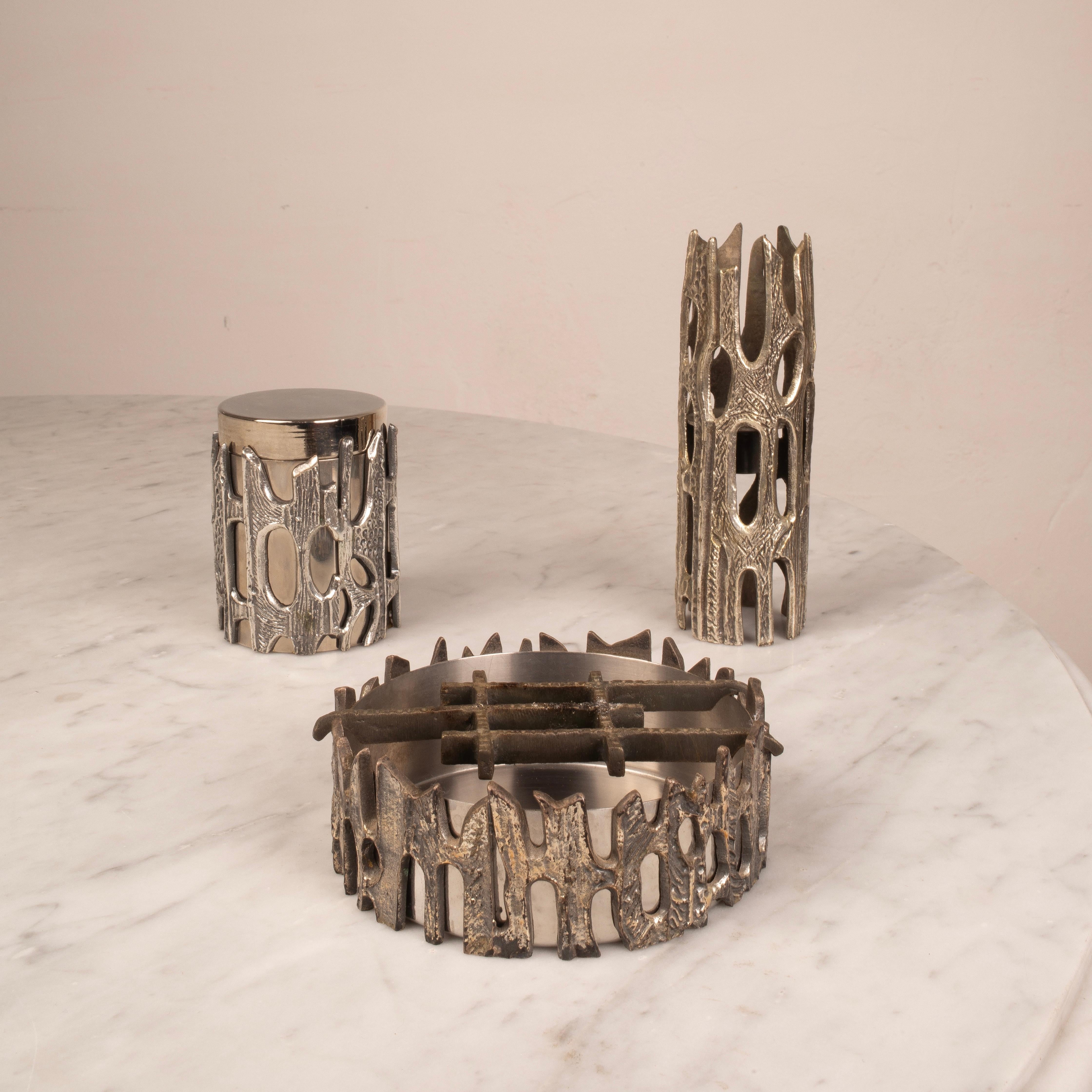 A rare and sculptural brutalist-style table set crafted in silvered bronze with a richly textured surface and organic openwork design. Produced by the renowned Italian art foundry Morbelli, the set includes three pieces: an ashtray, a cylindrical