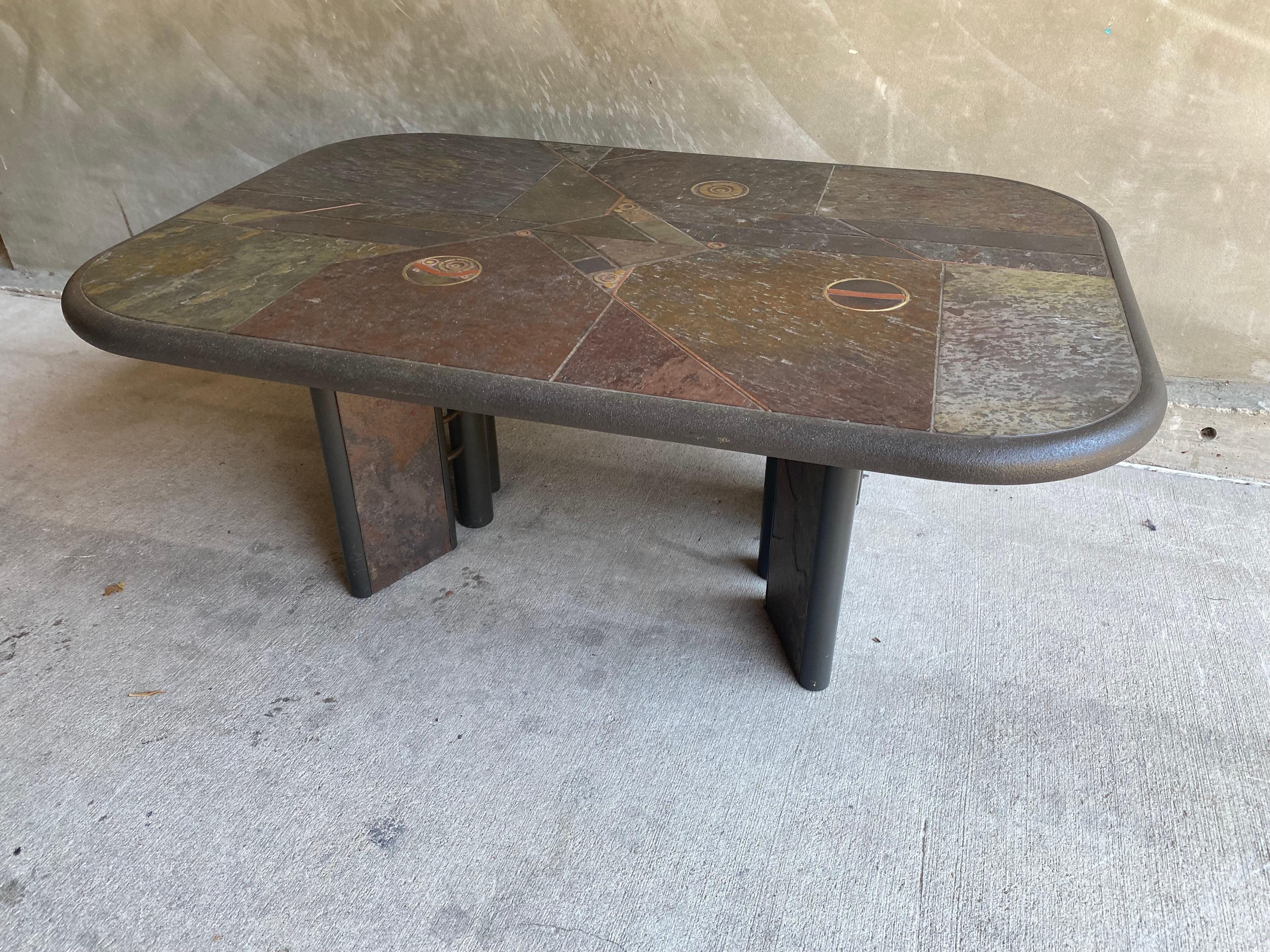 Brutalist cocktail table with slate style top and brass and copper inlay in asymmetric pattern. Belgium, 1970's

Matching smaller square shaped cocktail table or side table available on listing: LU1140230419032.
