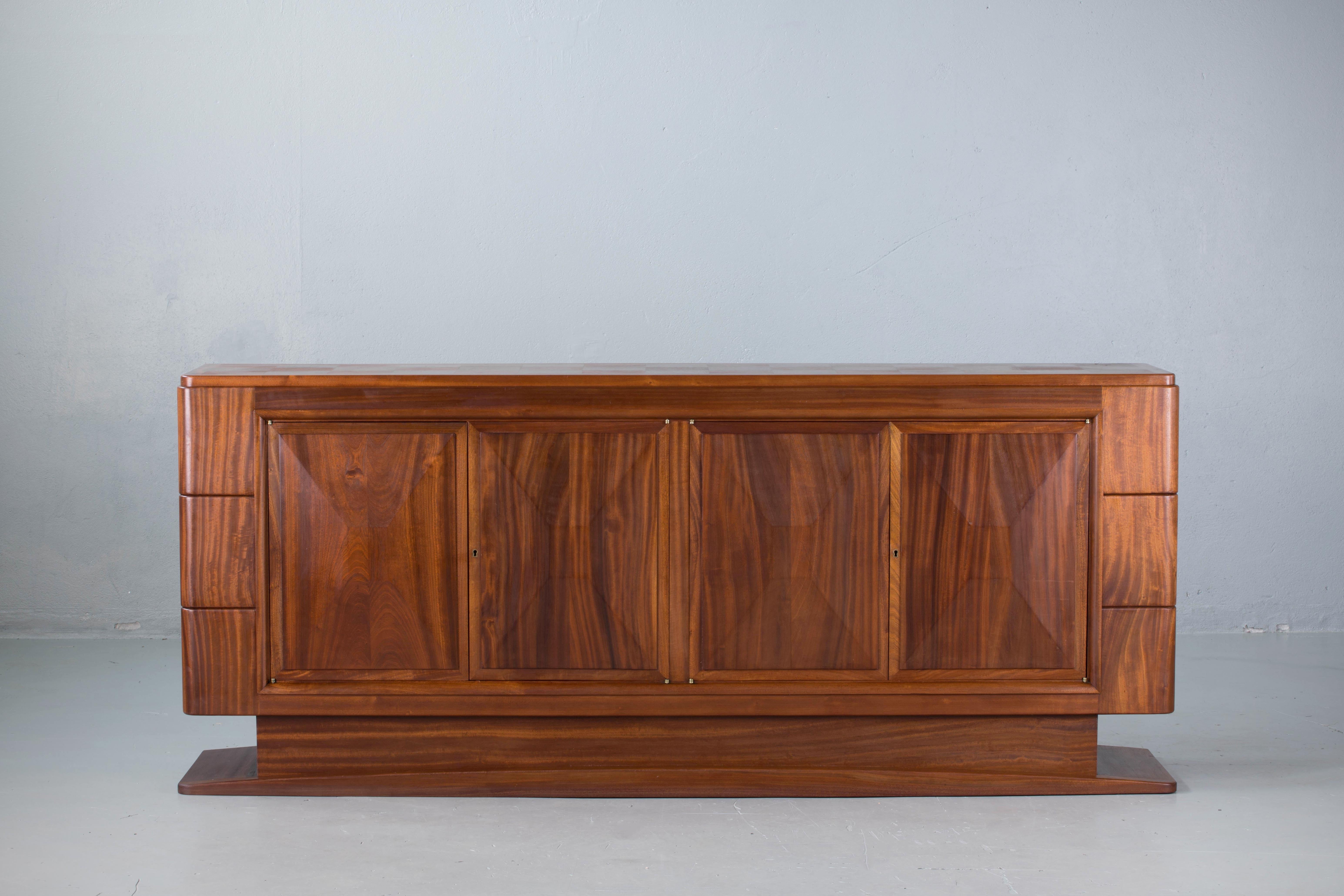 Credenza, solid mahogany, France, 1940s.
Large Art Deco Brutalist sideboard. This heavy Brutalist credenza seems to float on its elegant base. The credenza consists of four large storage facilities and covered with very detailed designed door