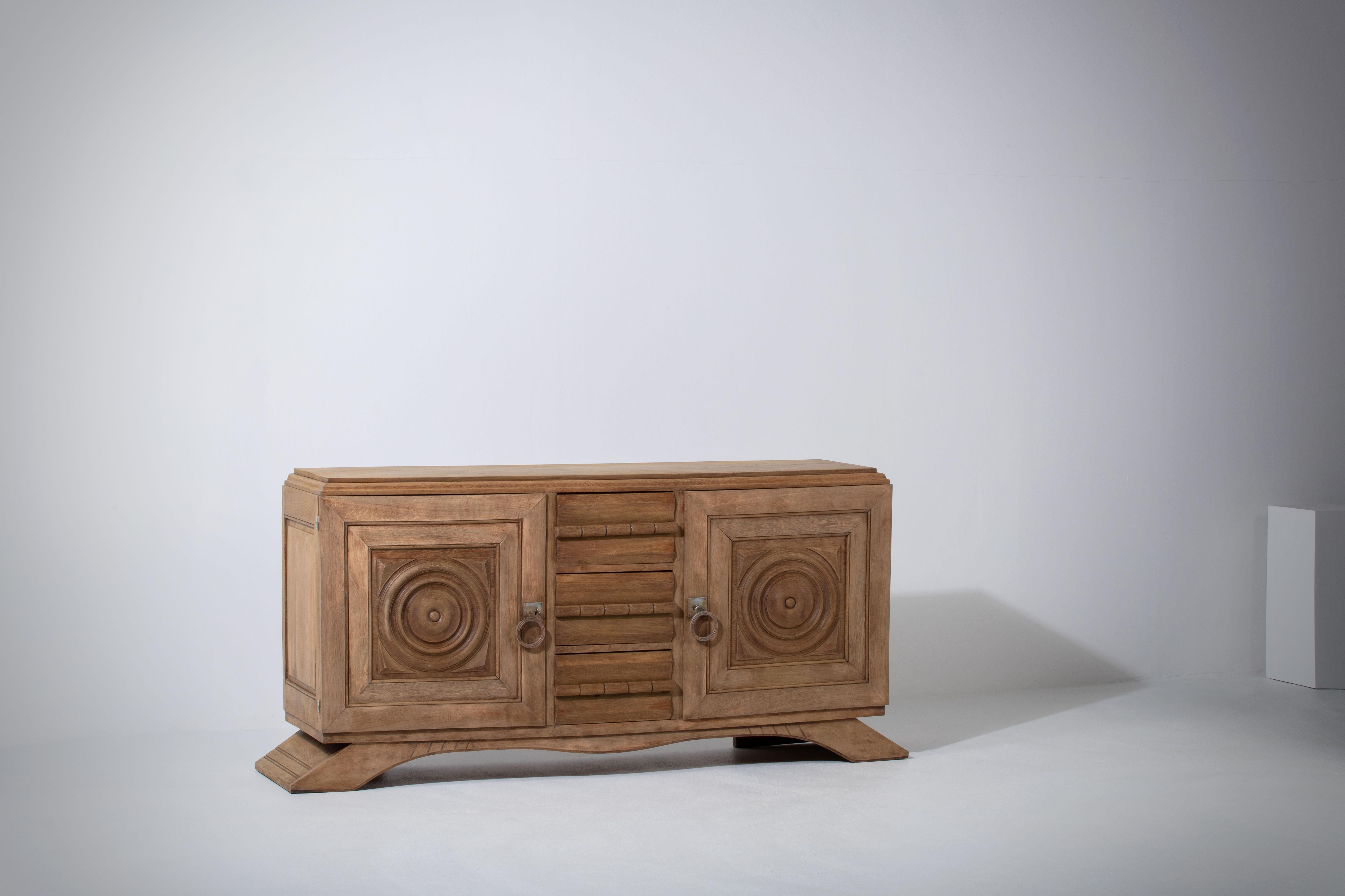 Credenza, solid oak, France, 1940s, attributed to Charles Dudouyt.
Large Art Deco Brutalist sideboard. 
The credenza consists of three central drawers and two storage facilities and covered with very detailed designed door panels. 
The refined