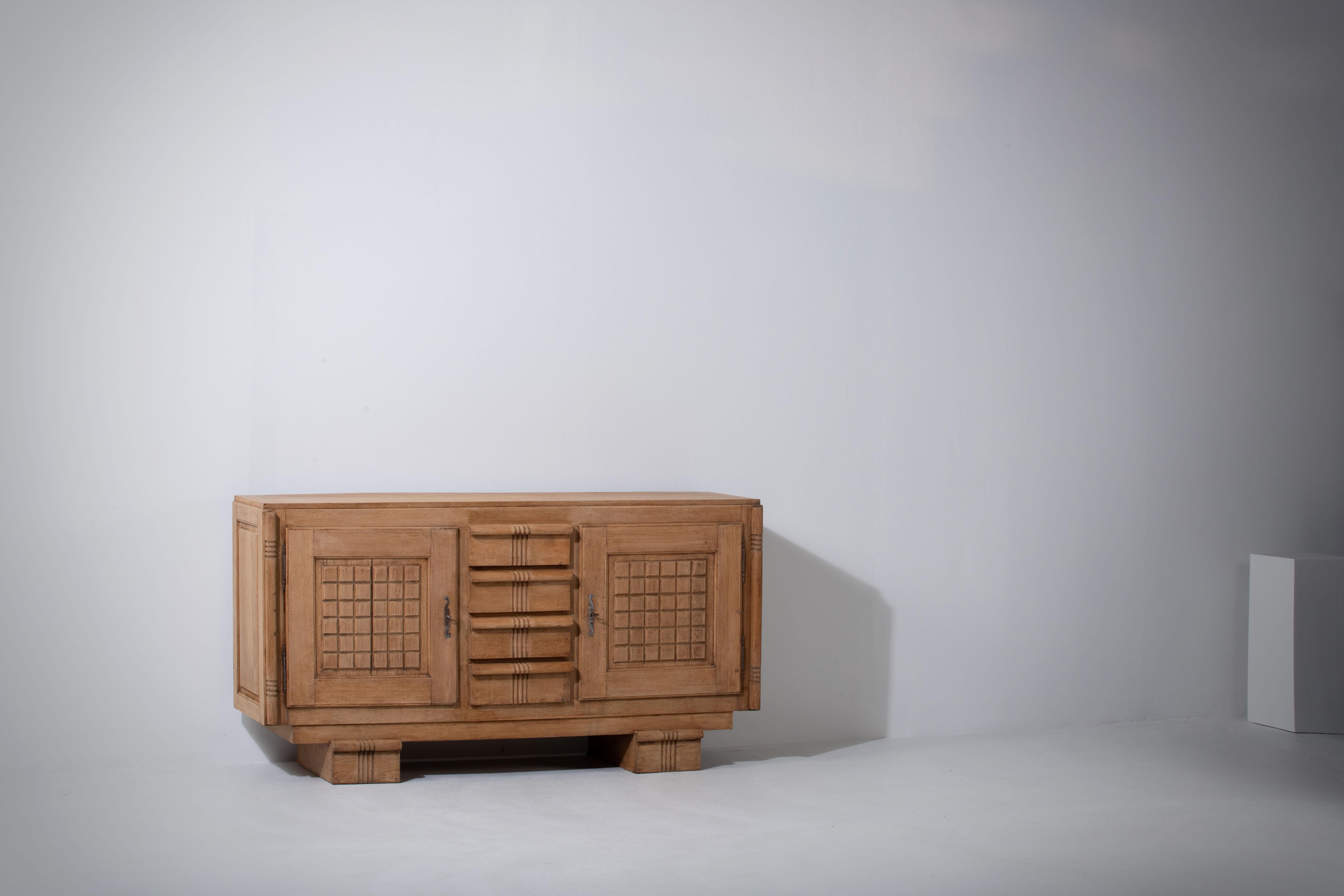 Credenza, solid oak, France, 1940s, Charles Dudouyt.
Large Art Deco Brutalist sideboard. 
The credenza consists of three central drawers and two storage facilities and covered with very detailed designed door panels. 
The refined wooden