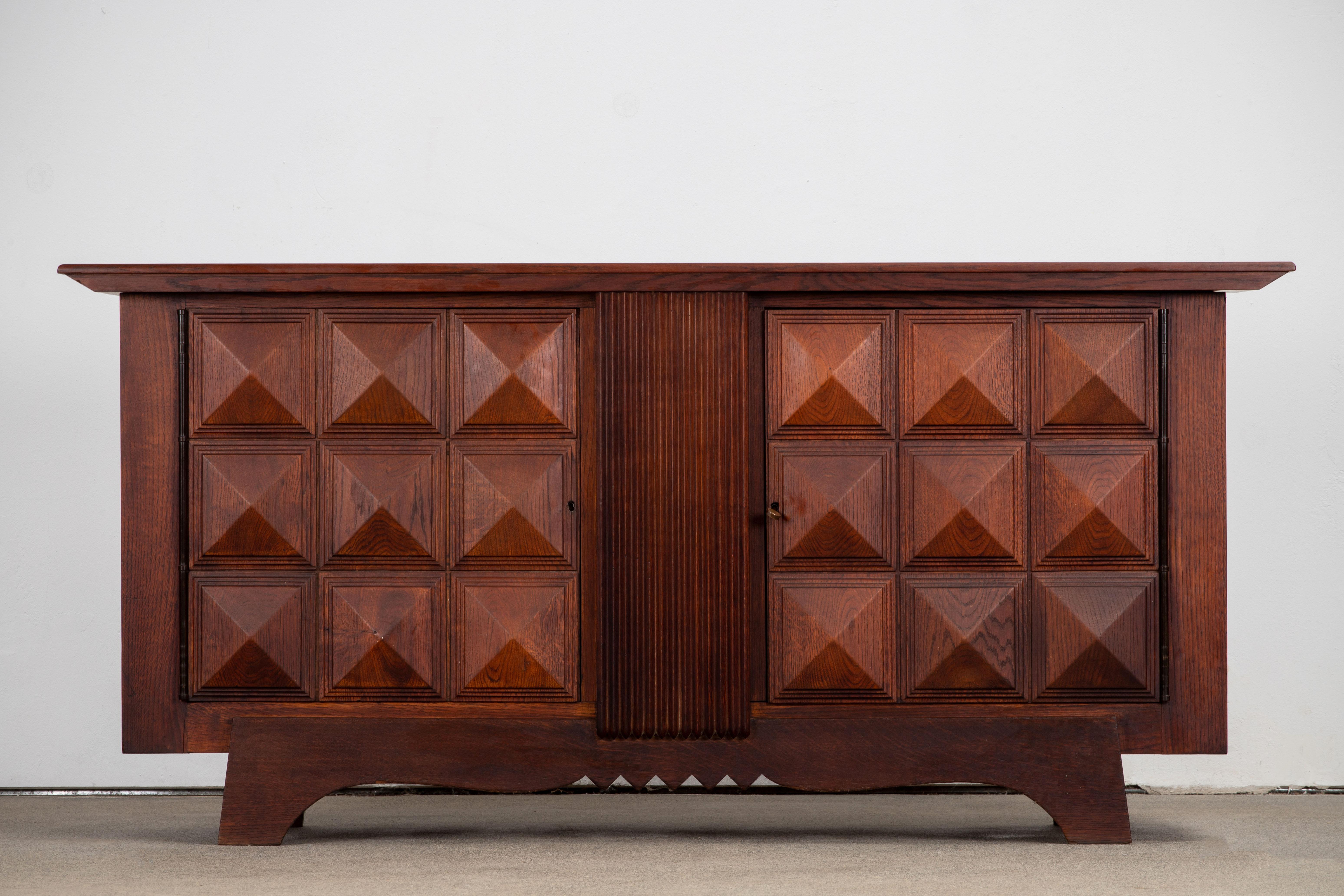 Credenza, solid oak, France, 1940s.
Large Art Deco Brutalist sideboard. This heavy Brutalist credenza seems to float on its elegant base. The credenza consists of two large storage facilities and covered with very detailed diamond designed door
