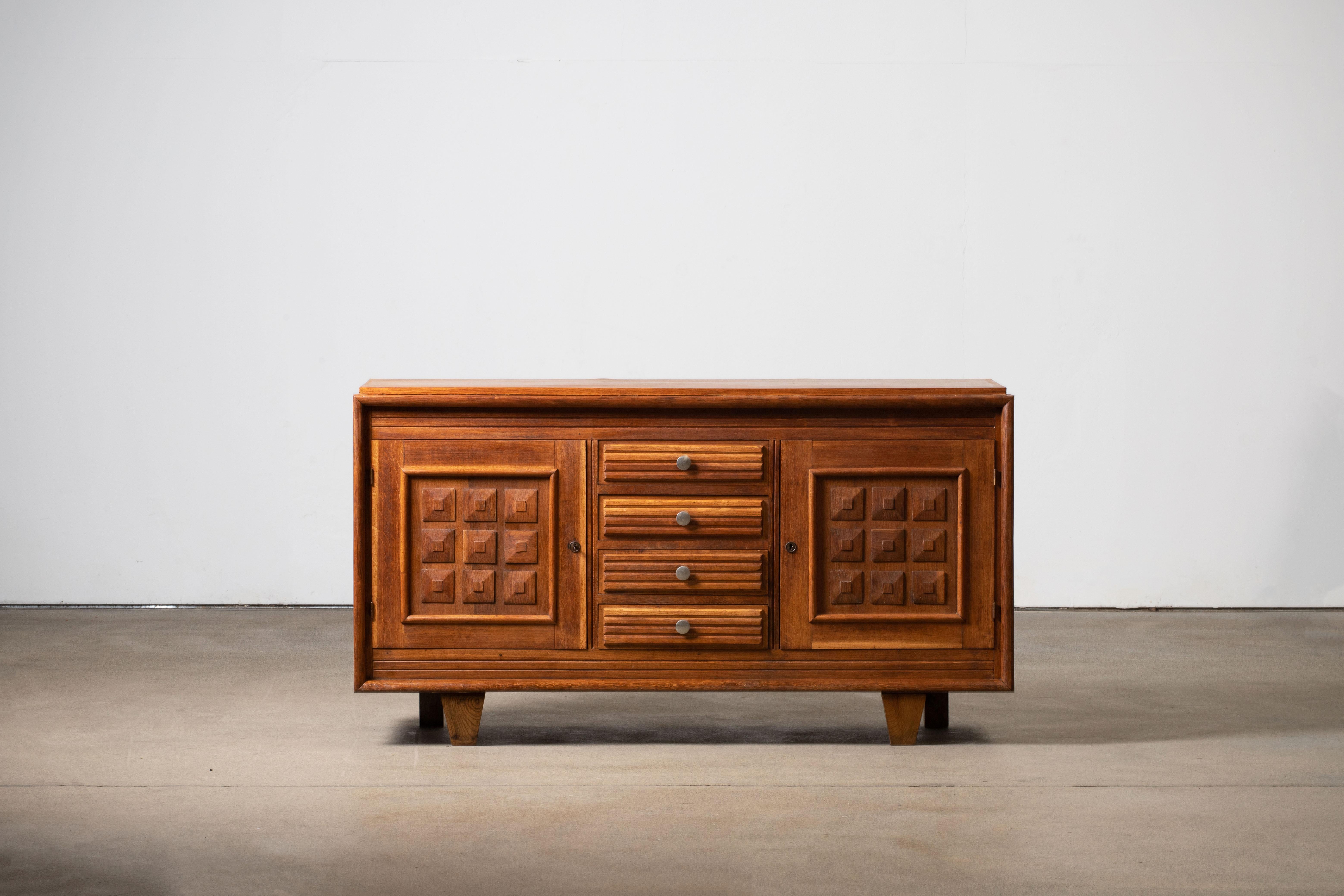 Credenza, solid oak, France, 1940s.
Large Art Deco Brutalist sideboard. 
The credenza consists of four central drawers and two storage facilities and covered with very detailed designed door panels. 
The refined wooden structures on the doors