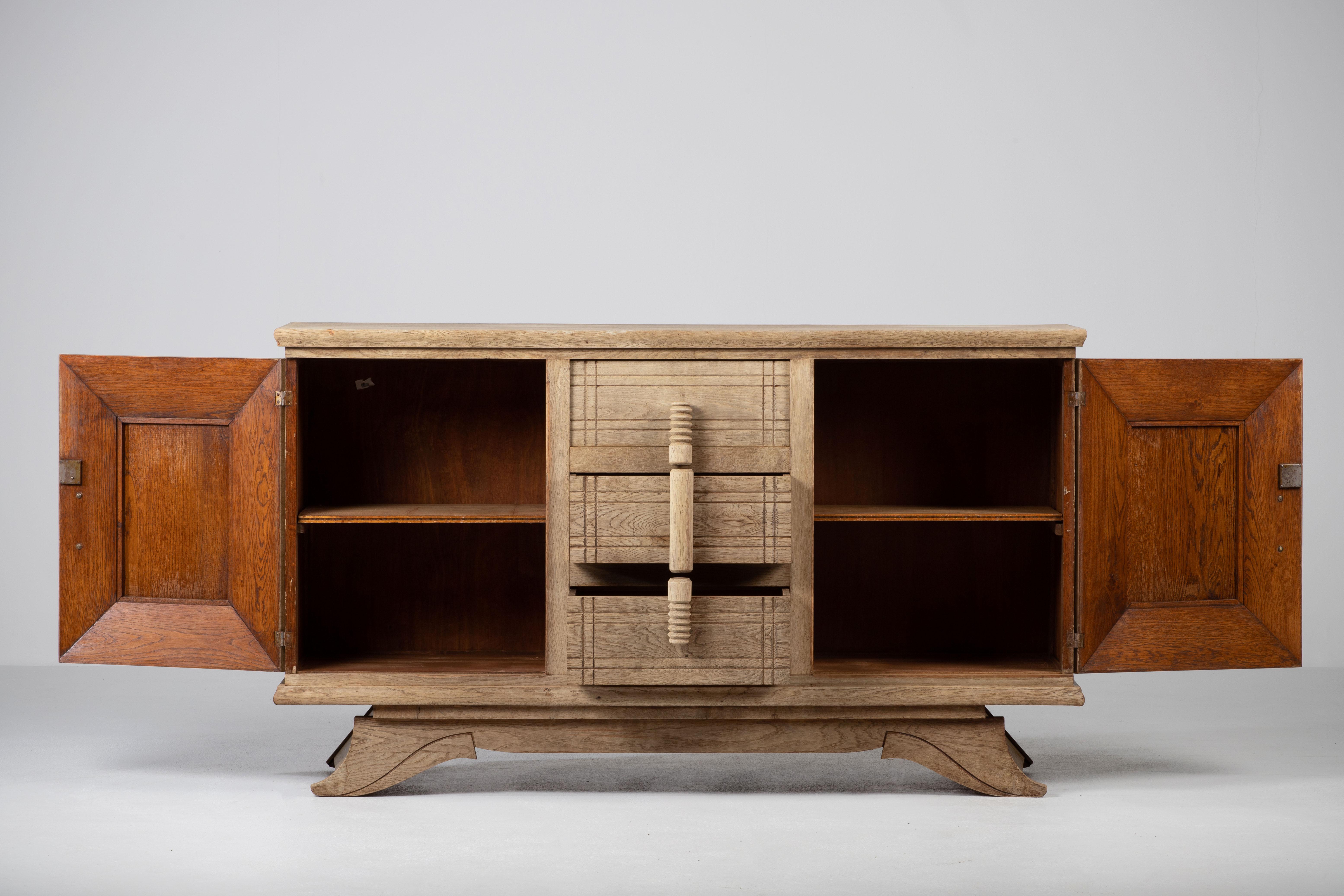 Credenza, solid oak, France, 1940s.
Large Art Deco Brutalist sideboard. 
This heavy Brutalist credenza features a minimal geometric design. The credenza consists of two storage facilities covered with geometric door panels and three drawers in the