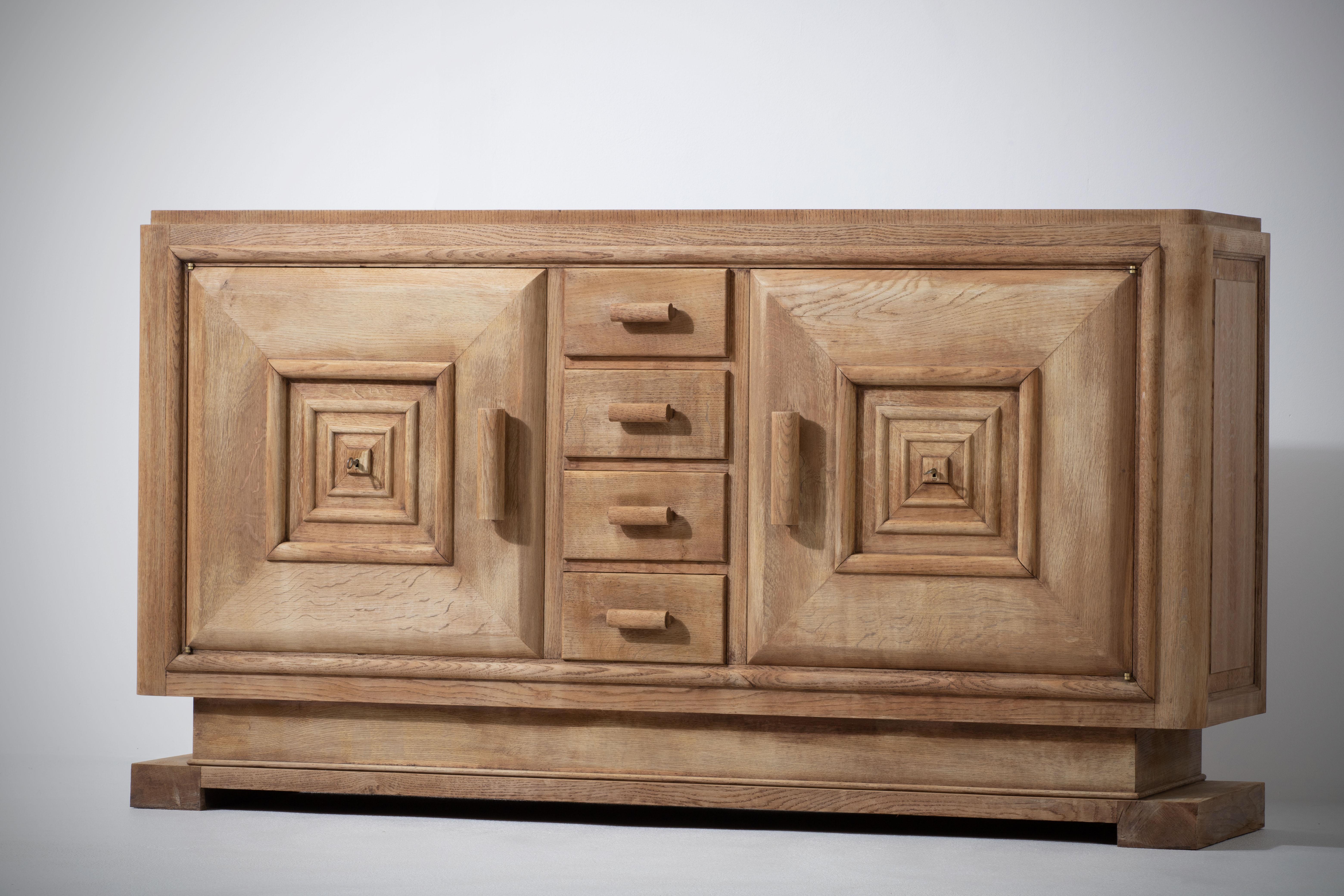 Credenza, solid oak, France, 1940s reminiscent of the work of Maxime Old.
Art Deco Brutalist sideboard. 
The credenza consists of two storage facilities and covered with very detailed designed doors and in the center, a drawers column.
 