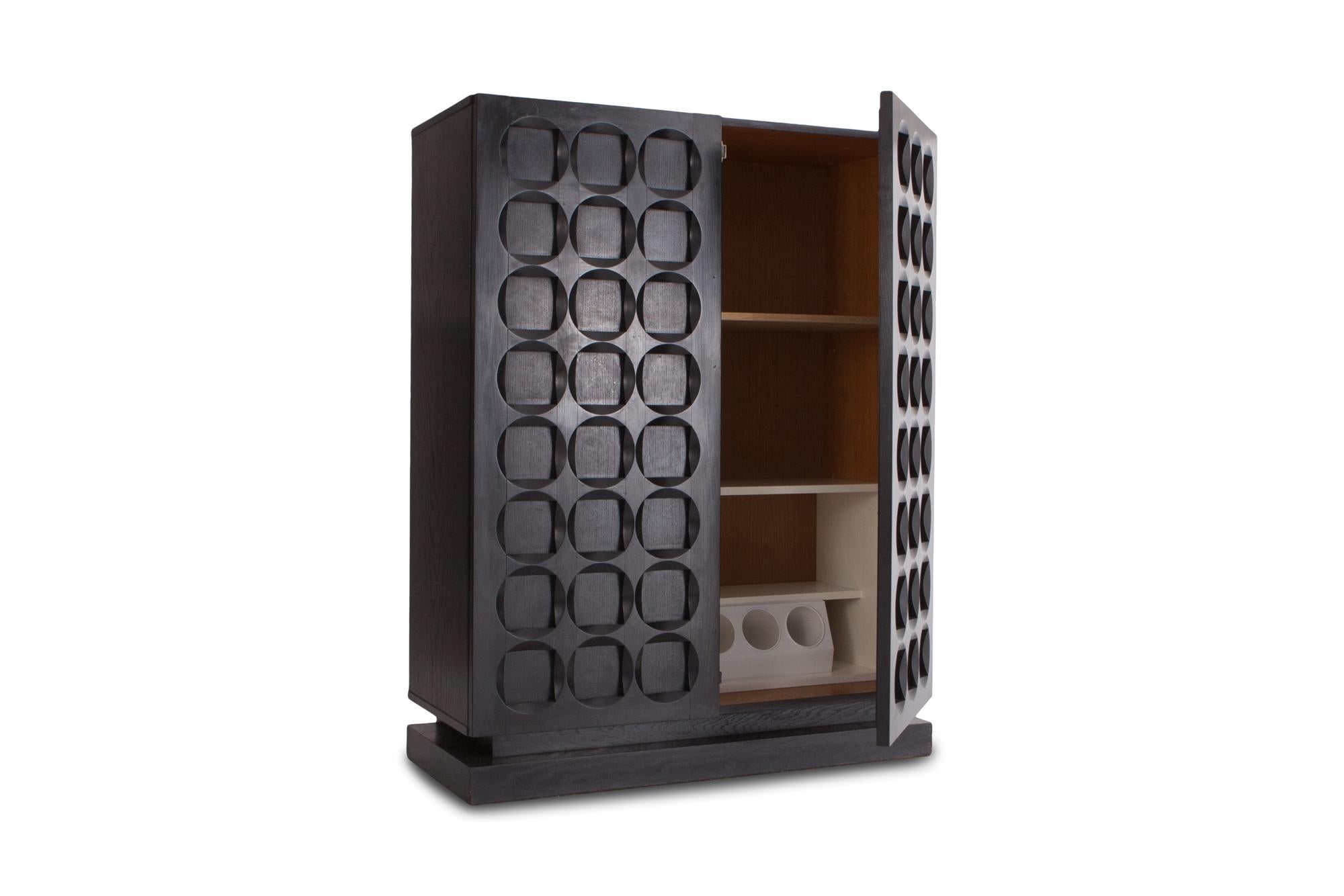 Black stained oak brutalist bar cabinet provided with door panels that show a high quality wood carved graphic pattern, consisting out of circles and squares that give it a strong and impressive appearance.

Resting on base with sharp lines,