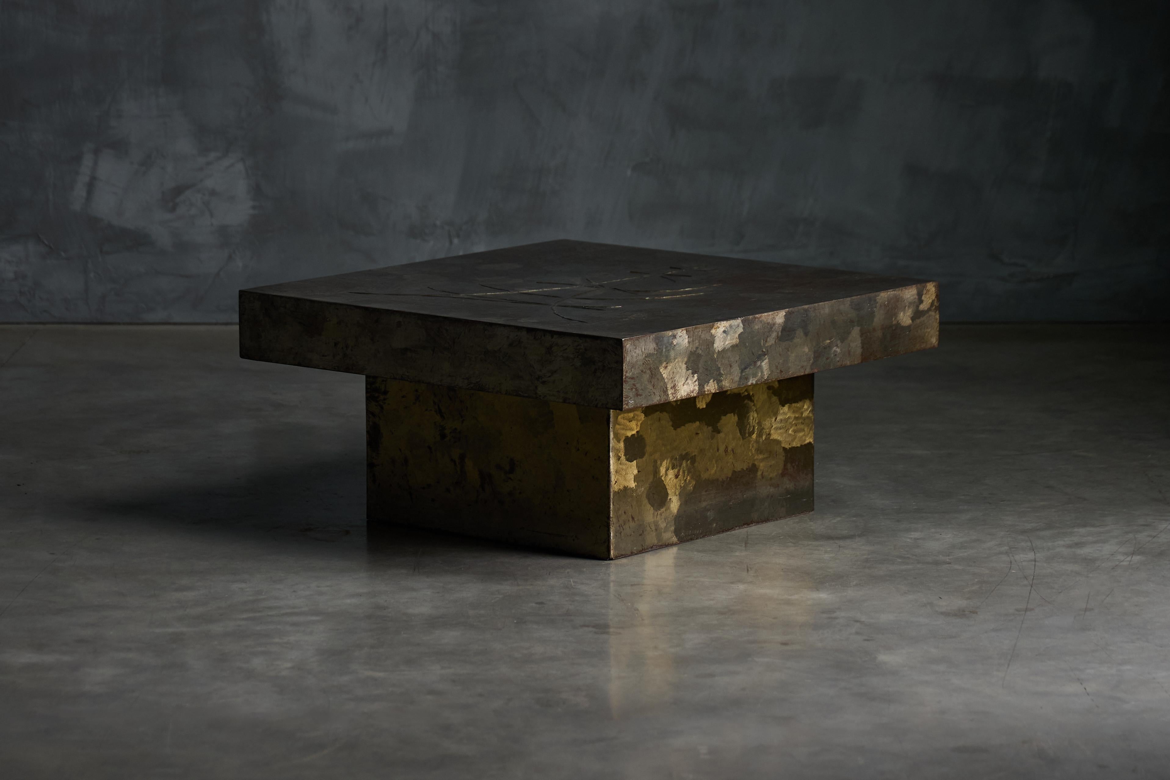 This brutalist coffee table in the style of Pia Manu from the 1970s is made entirely of steel. This sculptural piece features a square top with an etched botanical motif that lends organic softness to the otherwise bold, architectural form. The