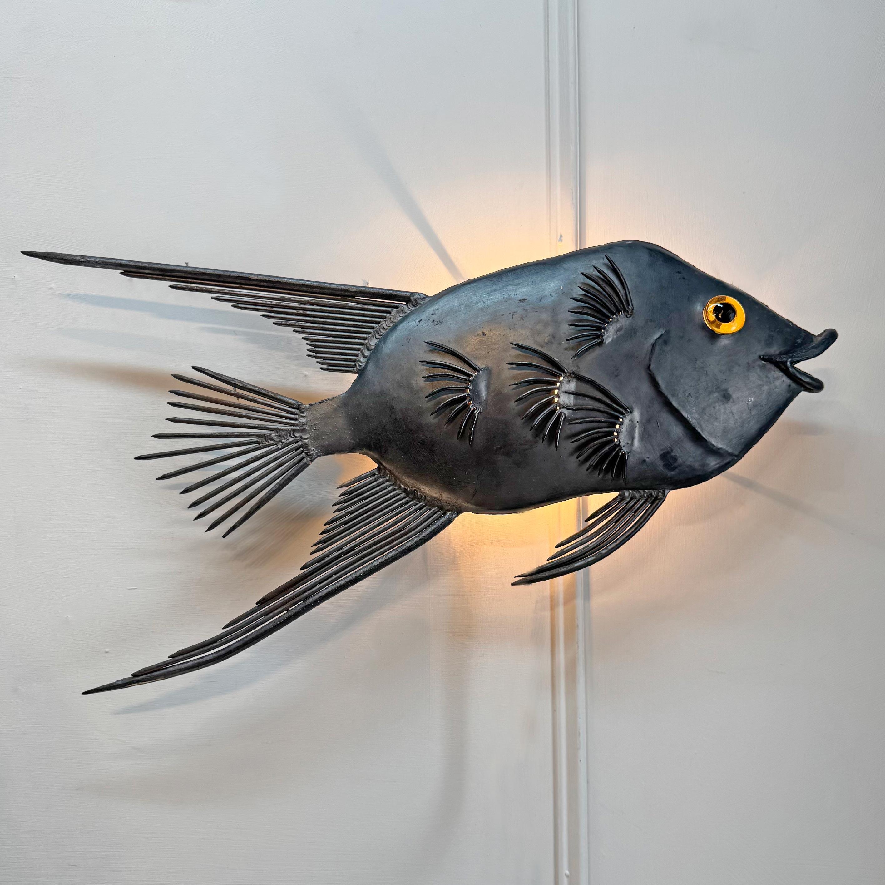 Una rarissima scultura brutalista illuminata in acciaio, realizzata a mano con chiodi e acciaio, modellata come un grande pesce tropicale e risalente agli anni Cinquanta.



Il bellissimo pesce lineare in acciaio scuro è dotato di un occhio in vetro