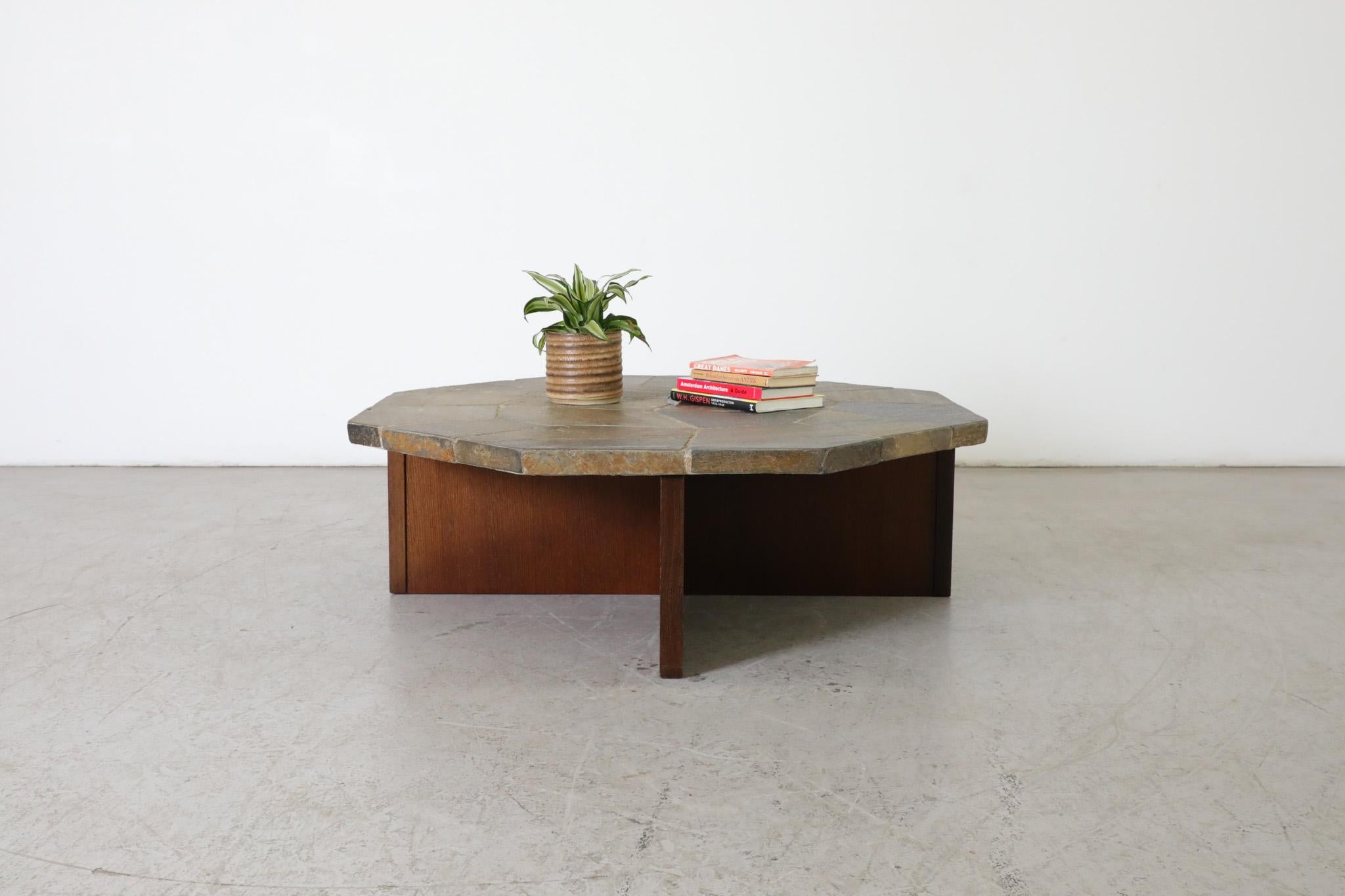Brutalist coffee table with heavy mosaic stone top on teak wood 'X' shaped base. A large stone slab decorated with inlaid cut stones on a beautiful detailed teak base. In original condition with some wear consistent with age and use.