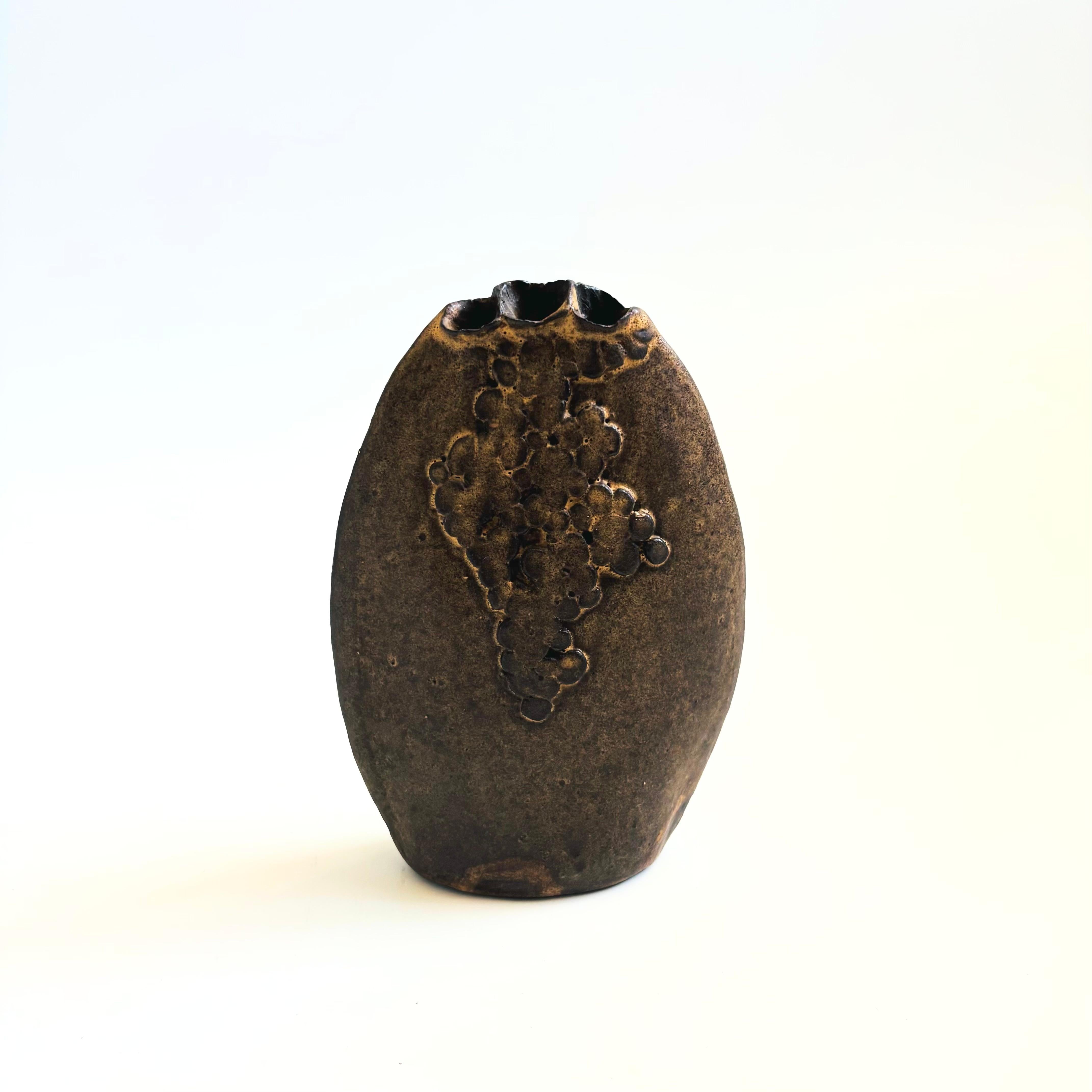 Un jarrón de capullos vintage de Studio Pottery. Forma ovalada plana con un diseño aplicado en un lado. Gran diseño brutalista. Tres agujeros formados en la parte superior del jarrón.


