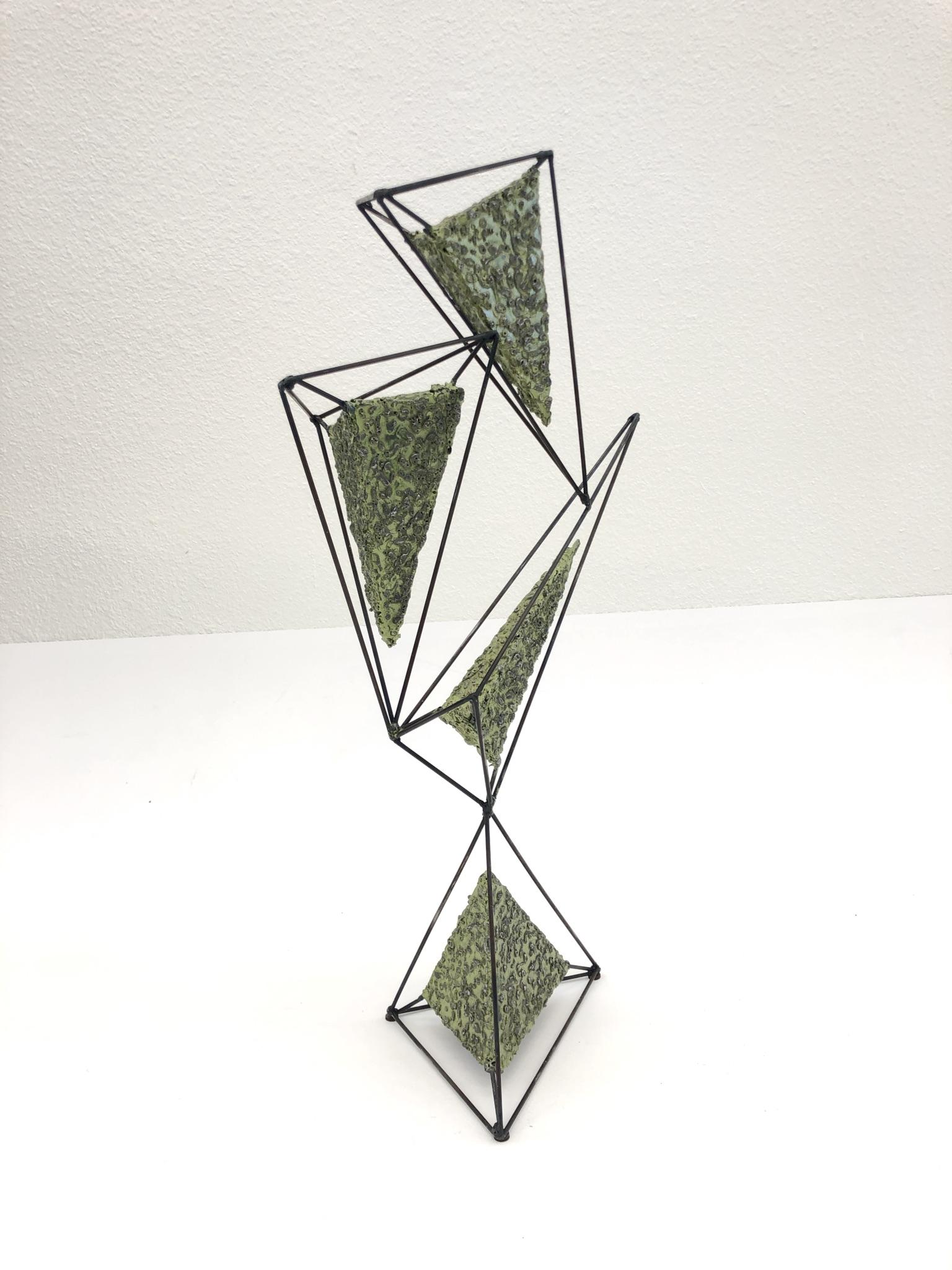 A spectacular geometric Brutalist studio sculpture by American sculptor John De La Rosa. The sculpture is constructed of steel and painted with a light olive green lacquer. 
Dimension: 25” high, 12”wide, 7” deep.