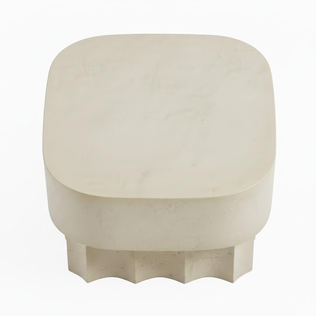 This sophisticated coffee table is a masterful blend of rich materiality and architectural form. The tabletop, a perfect square with gracefully rounded corners, is crafted from solid wood and finished with a aged plaster finish. This finish