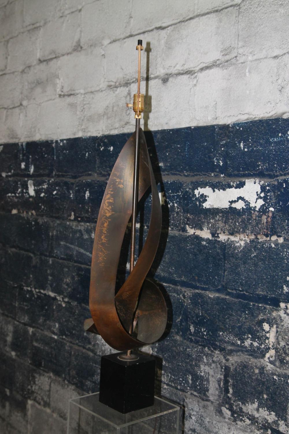 Nice oversized ribbon lamp from the Laurel Lamp Co. This brutalist style lamp was designed by Richard Barr. It has a great japan finish on the ribbon portion that sits on top of the black metal base. Its a very striking lamp and is in great vintage