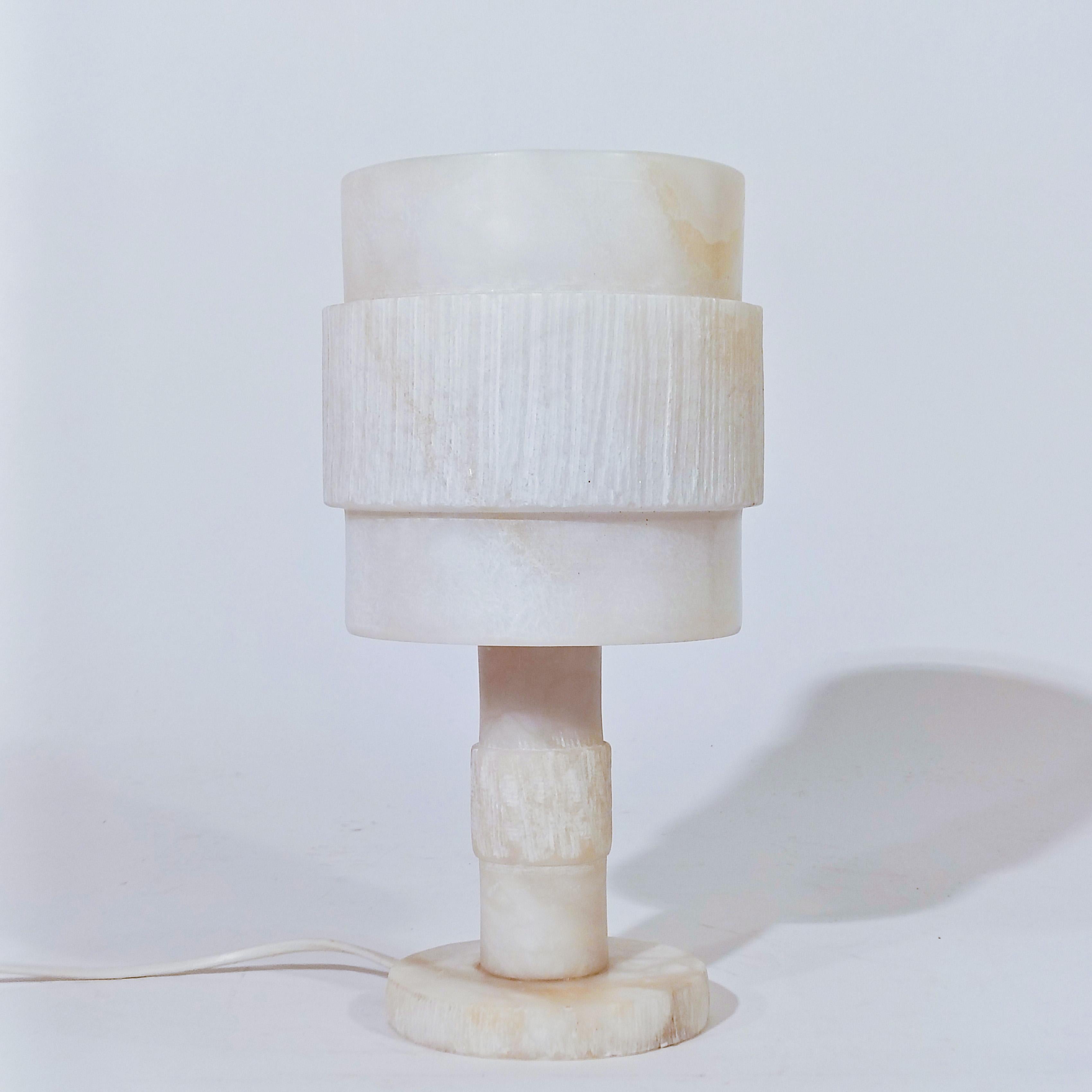 Turned alabaster table lamp, Spain, 1950s. Made entirely of turned alabaster, which has been sculpted and worked by hand in relief, with a natural finish. It consists of 3 overlapping cylinders glued together forming a torch-like lamp, offering a