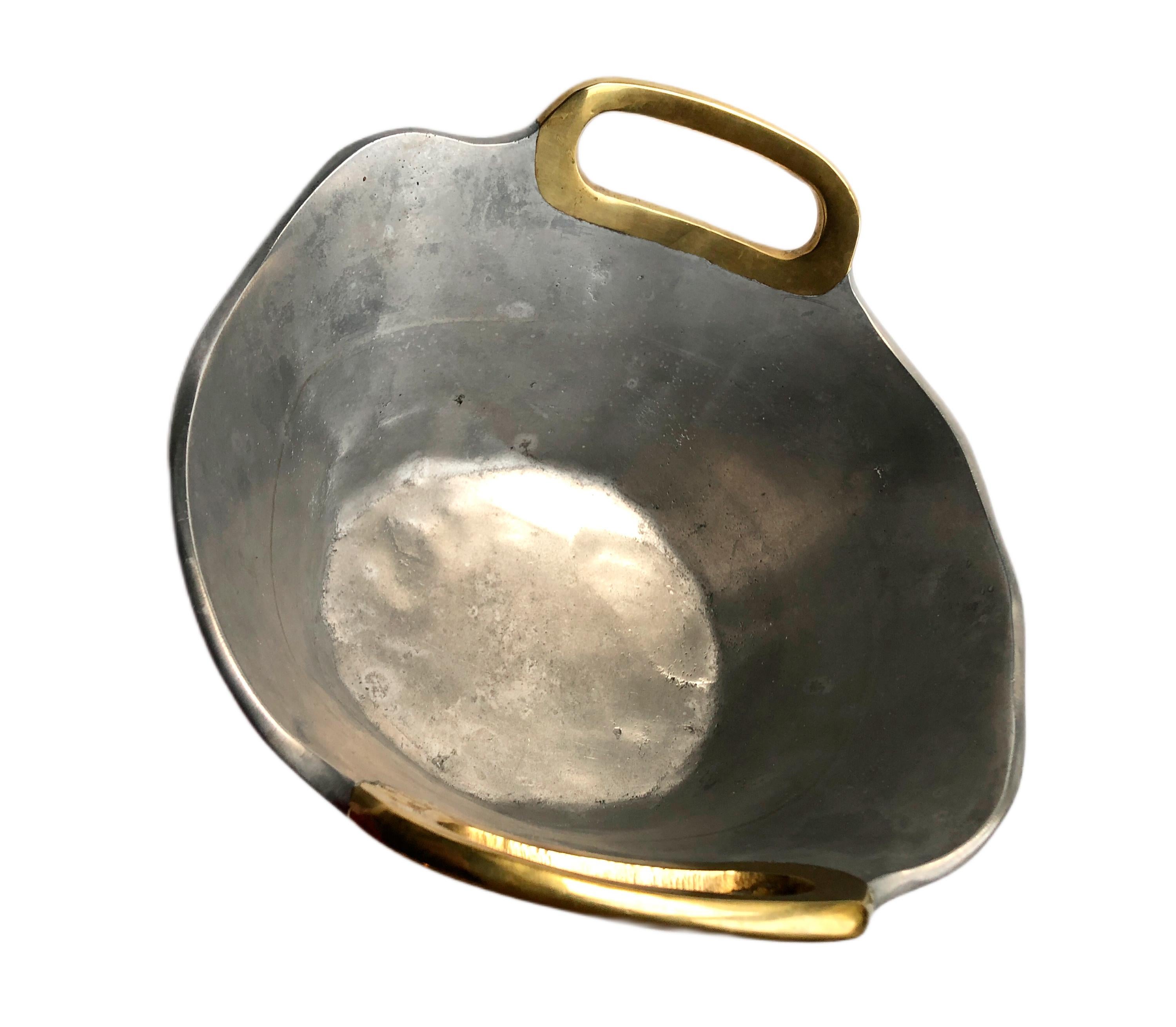 Brutalist Style Vintage Bowl in Brass Aluminium by David Marshall, Circa 1970s.  Double brass handles by the Scottish artist David Marshall. The bottom has the trademark leather base also with maker's mark somewhat faded, (picture).    

About the