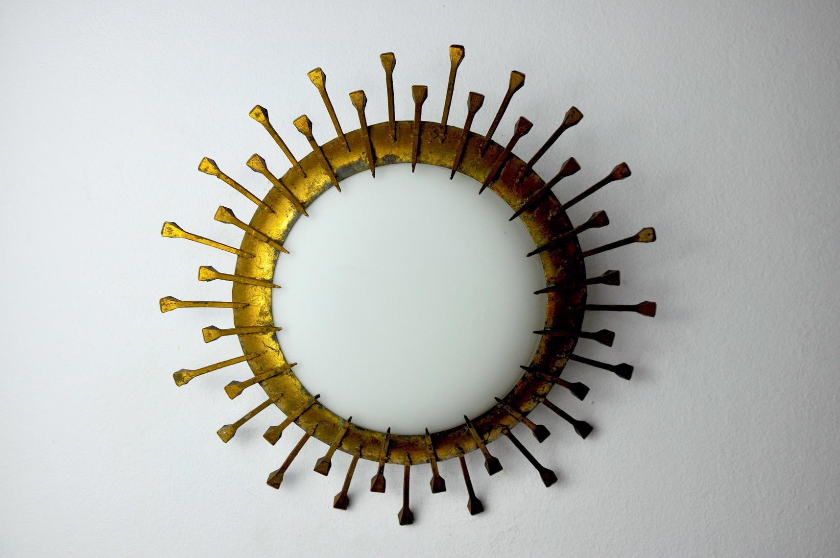 Superb Brutalist style sun wall lamp, designed and produced in Italy in the 1960s. This wall lamp is composed of a wrought iron structure decorated with gold leaf and a white opaline crystal. Unique object that will illuminate wonderfully and bring