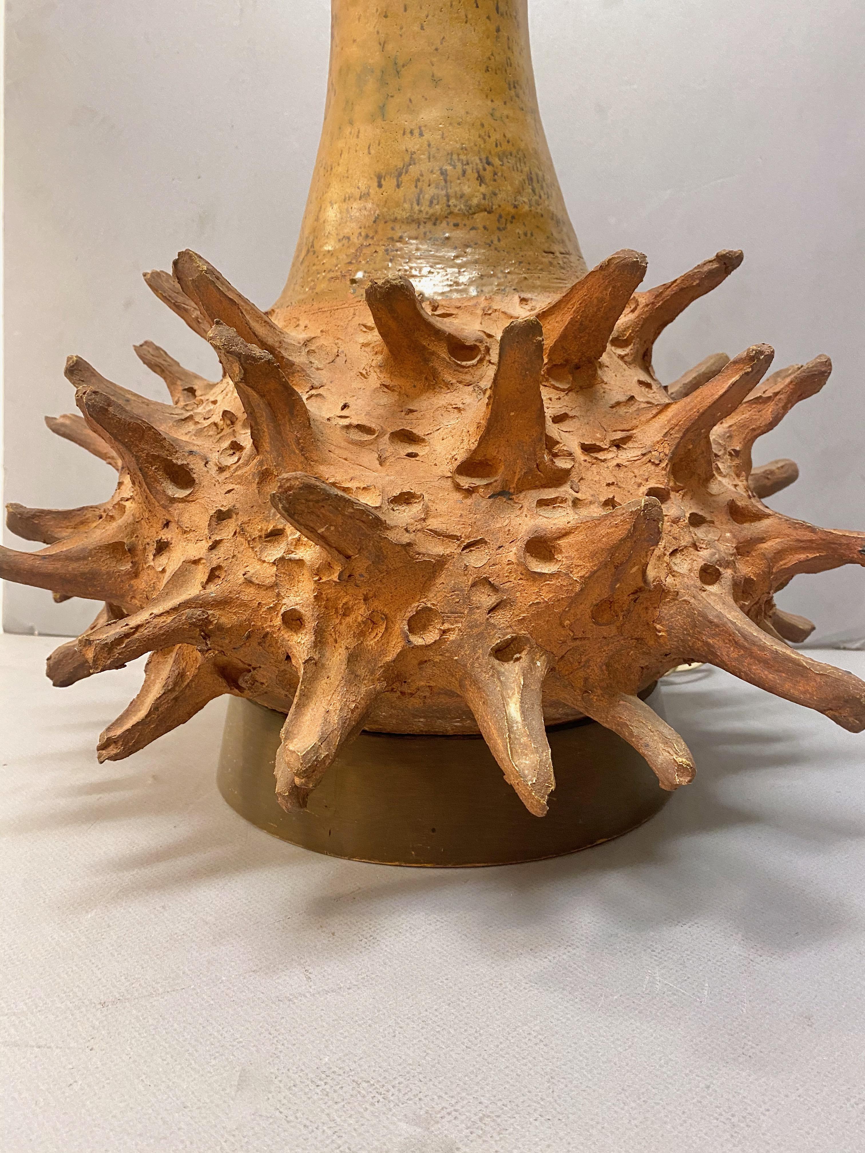 This is a stunning mid-century Brutalist artist-made terra cotta lamp. The long-necked spiked bulbous base is monumental in size and a show-stopper. The lamp measures an impressive 43 inches in height--the addition of an appropriate shade would