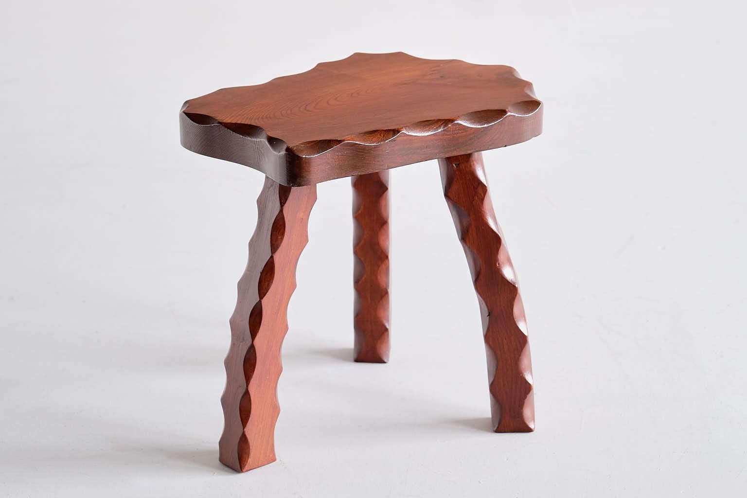 This sculptural stool was produced in France in the late 1950s. The striking design consists of an organic shaped top with a carved edge in a serrated pattern and three legs with a similar carved pattern on all sides. All parts are made of solid elm