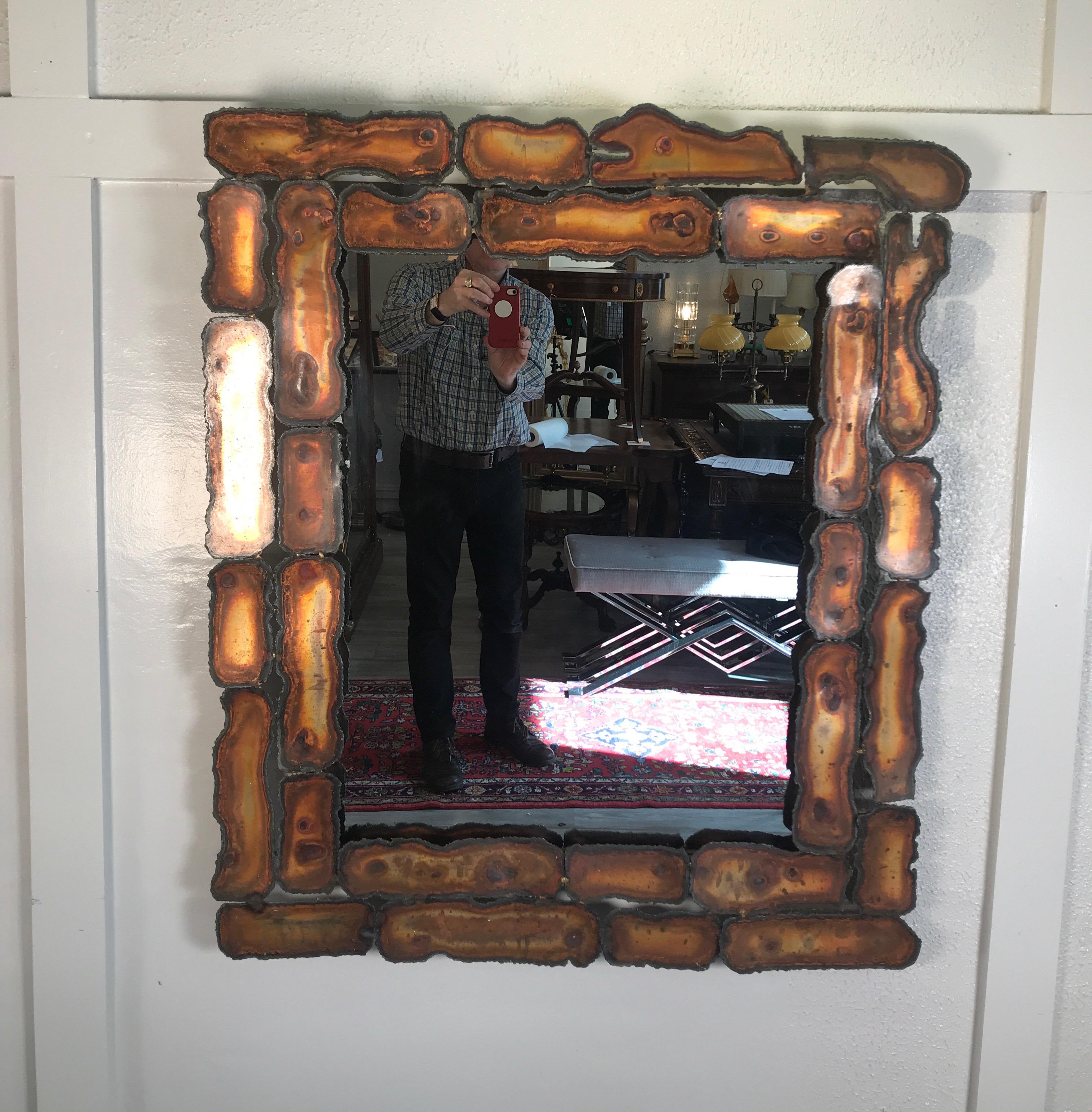 Nice large rectangular Brutalist style mixed metal framed mirror with rough cut edges with a nice patination for the heat of the torch. The frame is made up from panes of metal colorized from the heat and fashioned to make the rectangular frame.