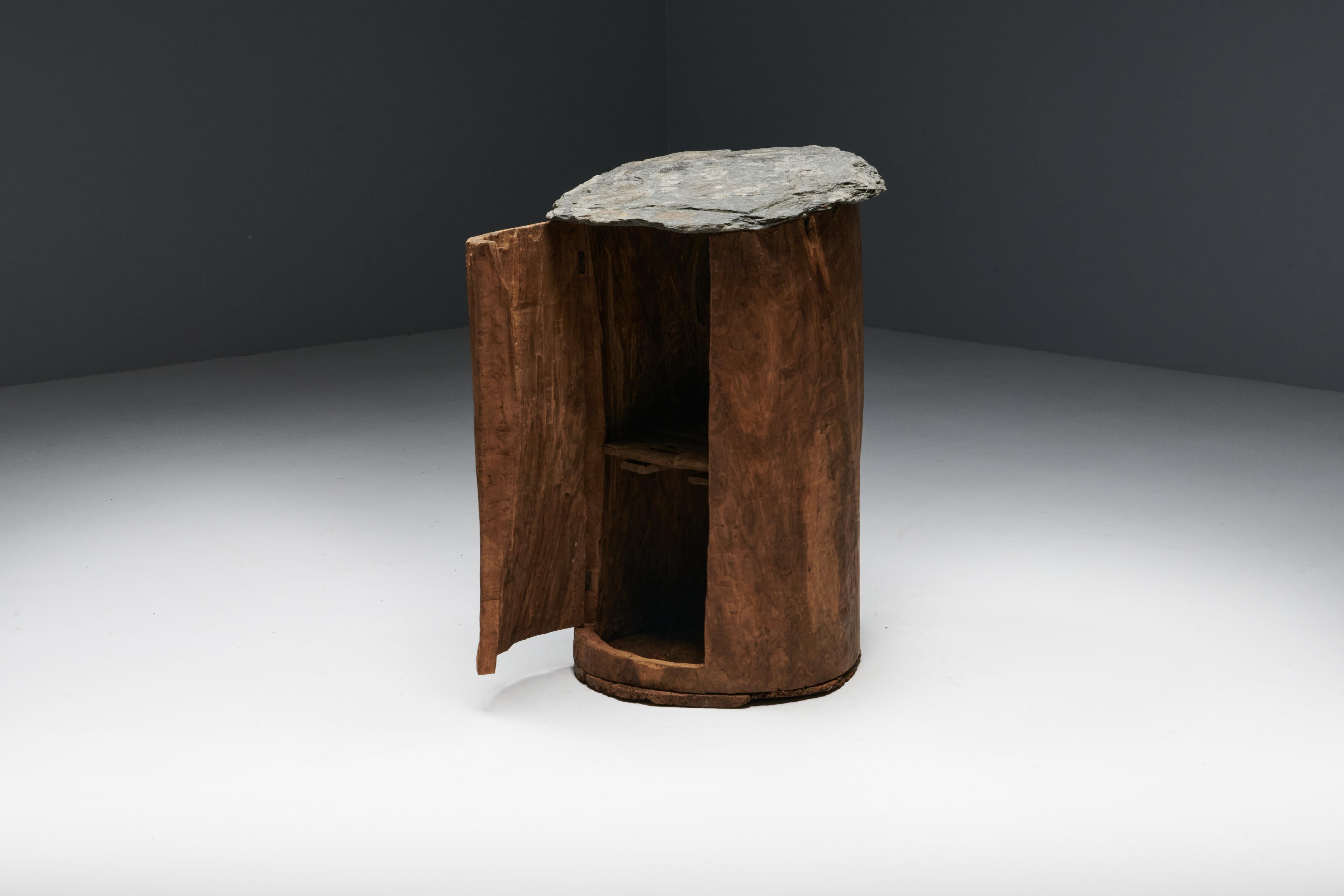 This unique rustic folk art cabinet is handcrafted from a solid tree trunk and finished with exquisite slate, seamlessly blending natural beauty with functional design. Harking back to a bygone era when these creations were known as 