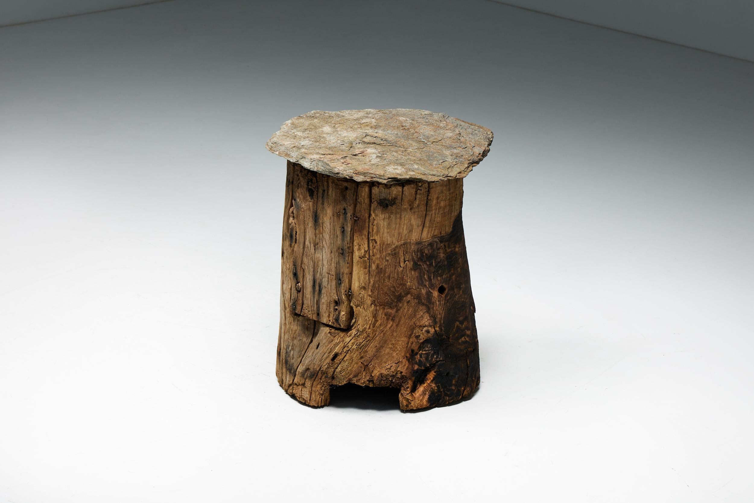 Handcrafted from a solid tree trunk, this unique rustic folk art piece serves as both a side table and a cabinet. Topped with beautiful slate, it seamlessly blends natural beauty with functional design. This exceptional piece of furniture harks back