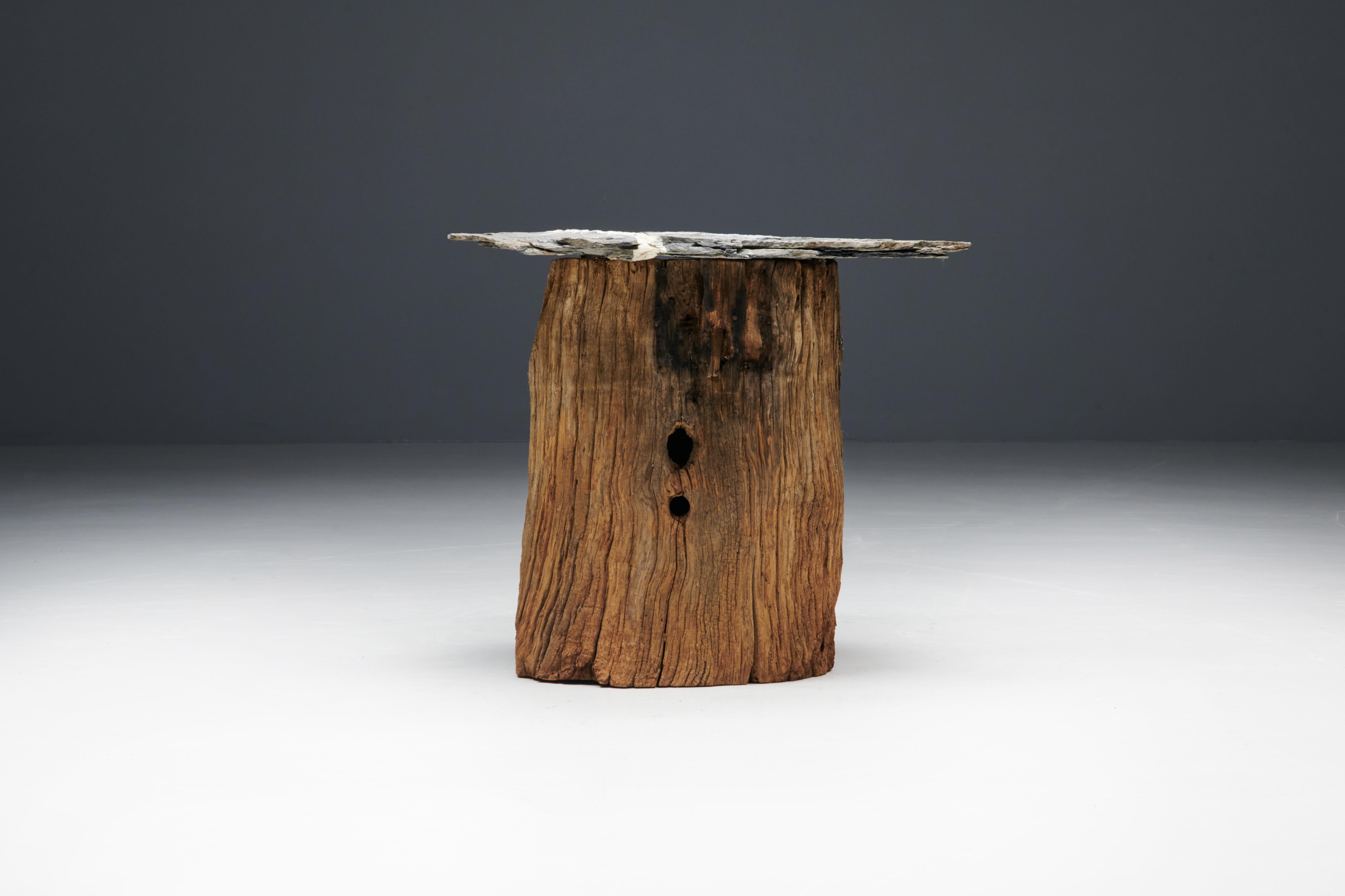Folk art side table, handcrafted from a solid tree trunk with a beautiful slate top. This side table is a harmonious fusion of natural beauty and functional design. We have matching side tables and storage pieces available in other offerings, each a