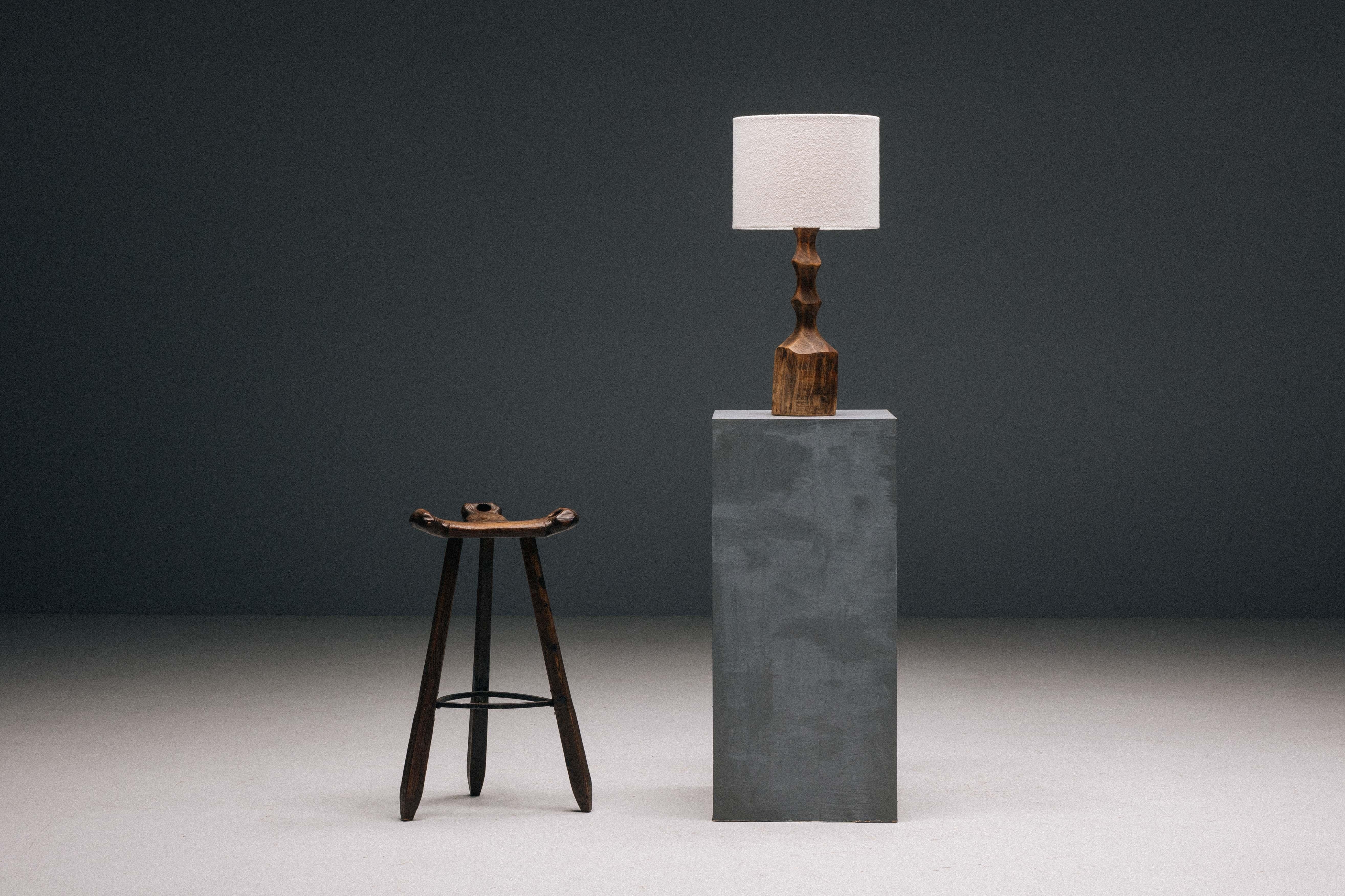 Lampe de table brutaliste en bois massif des années 1970, incarnant l'essence du design brutaliste avec son esthétique brute et sans concession. Sculptée à la main dans un seul bloc de bois, cette lampe est une œuvre d'art unique qui témoigne de