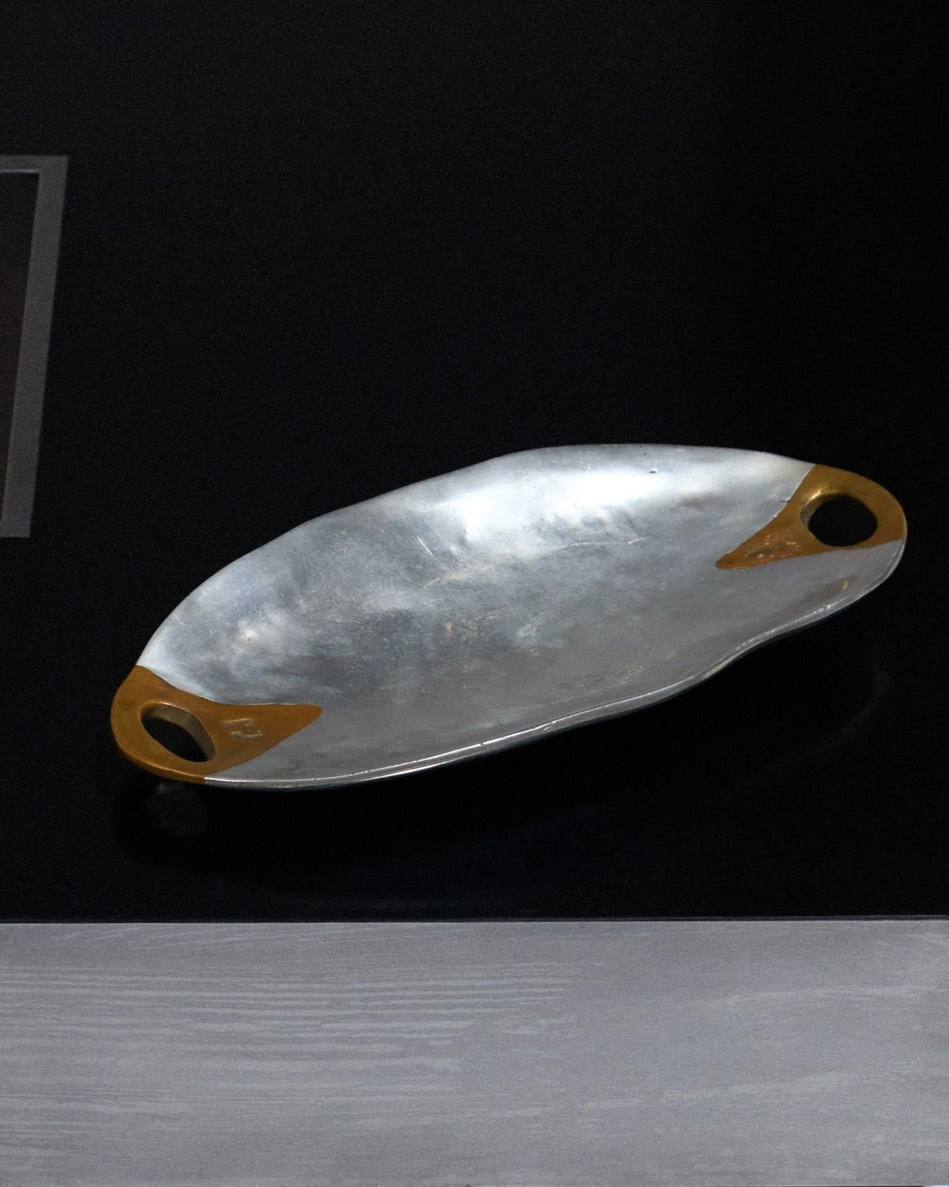 Oval Brutalist Tray or Large Catchall, David Marshall, 1980s, Spain.
Cast aluminum body with two triangular brass inlays at the ends, characteristic of the post-modernist style. Minor signs of wear consistent with age and use. Excellent
