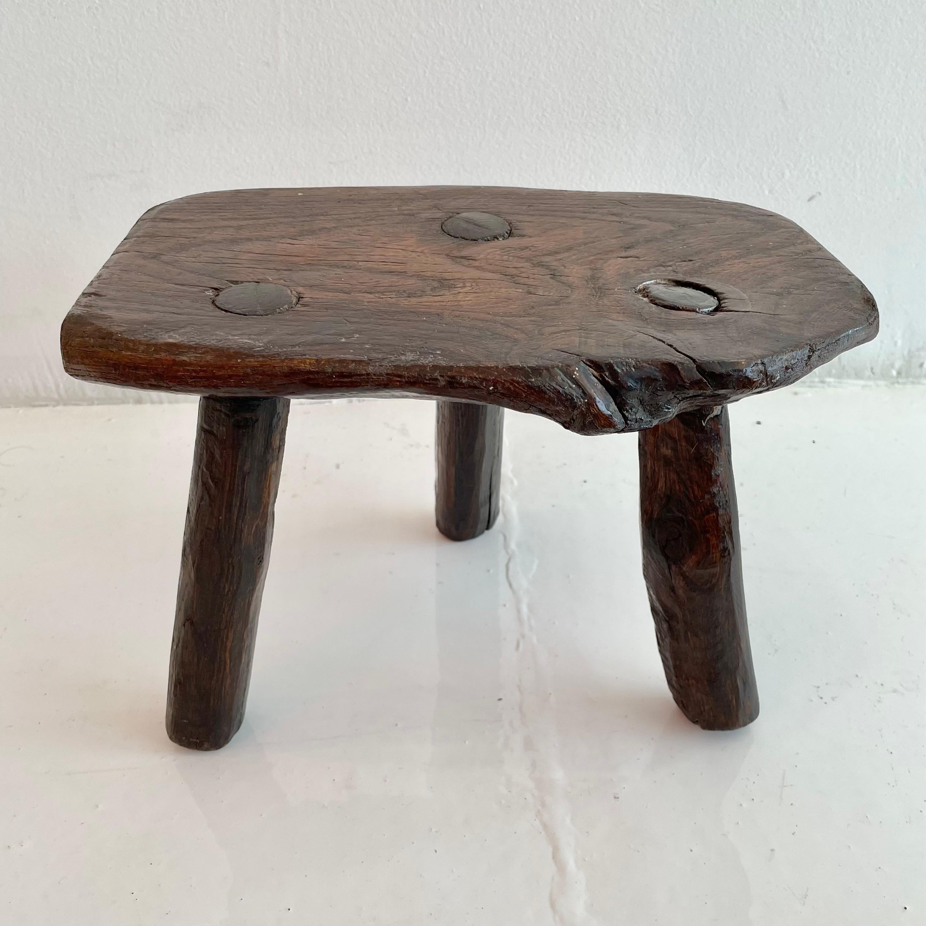 Stubby wooden tripod stool, made in France, circa 1950s. Thick brutalist seat with three rounded legs. No nails or hardware. Great shape and character. Petite stool with beautiful presence. Great vintage condition. Perfect for books or objects as